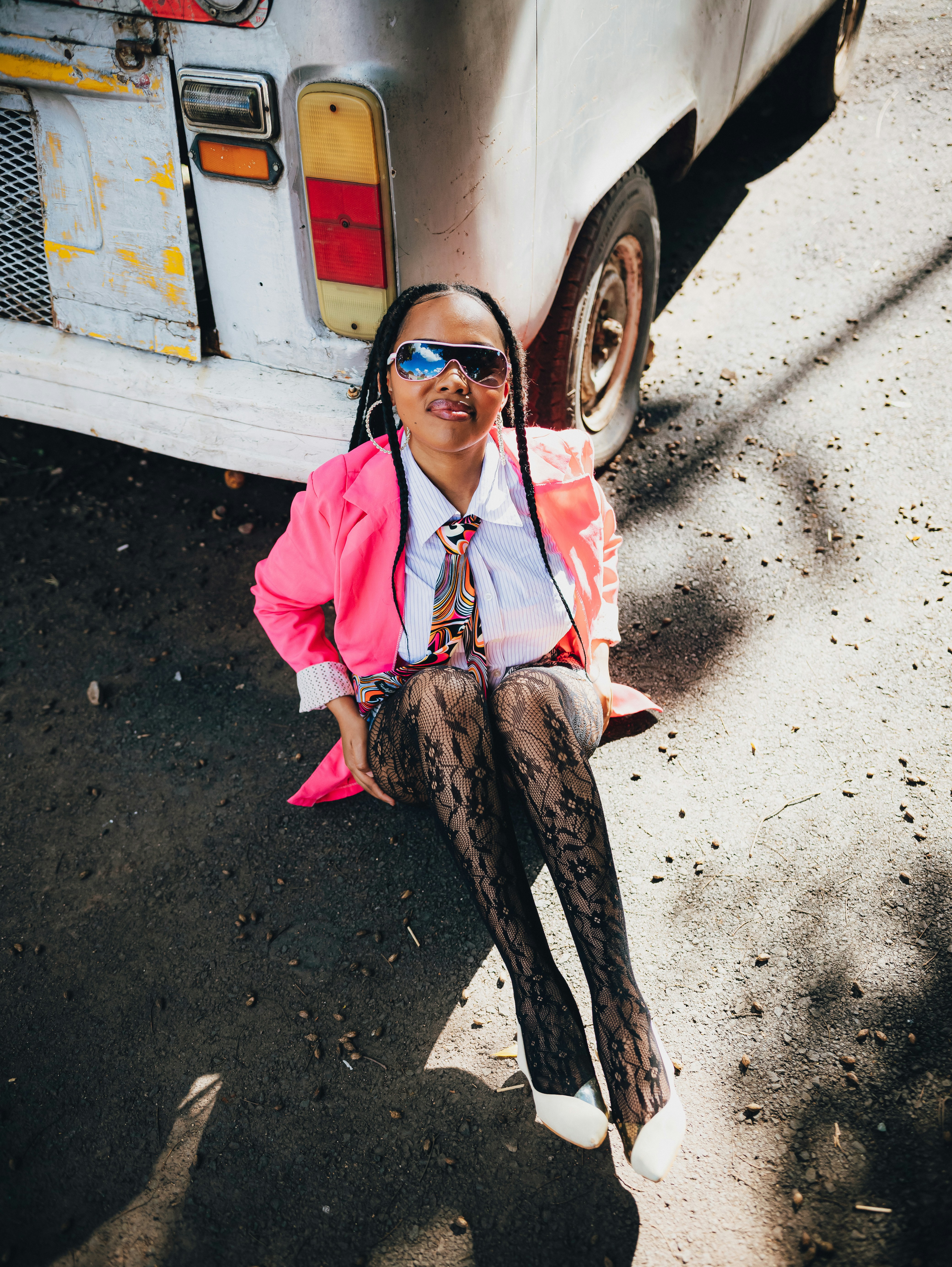 Mulher de blazer rosa e meia-calça estampada sentada ao lado da van