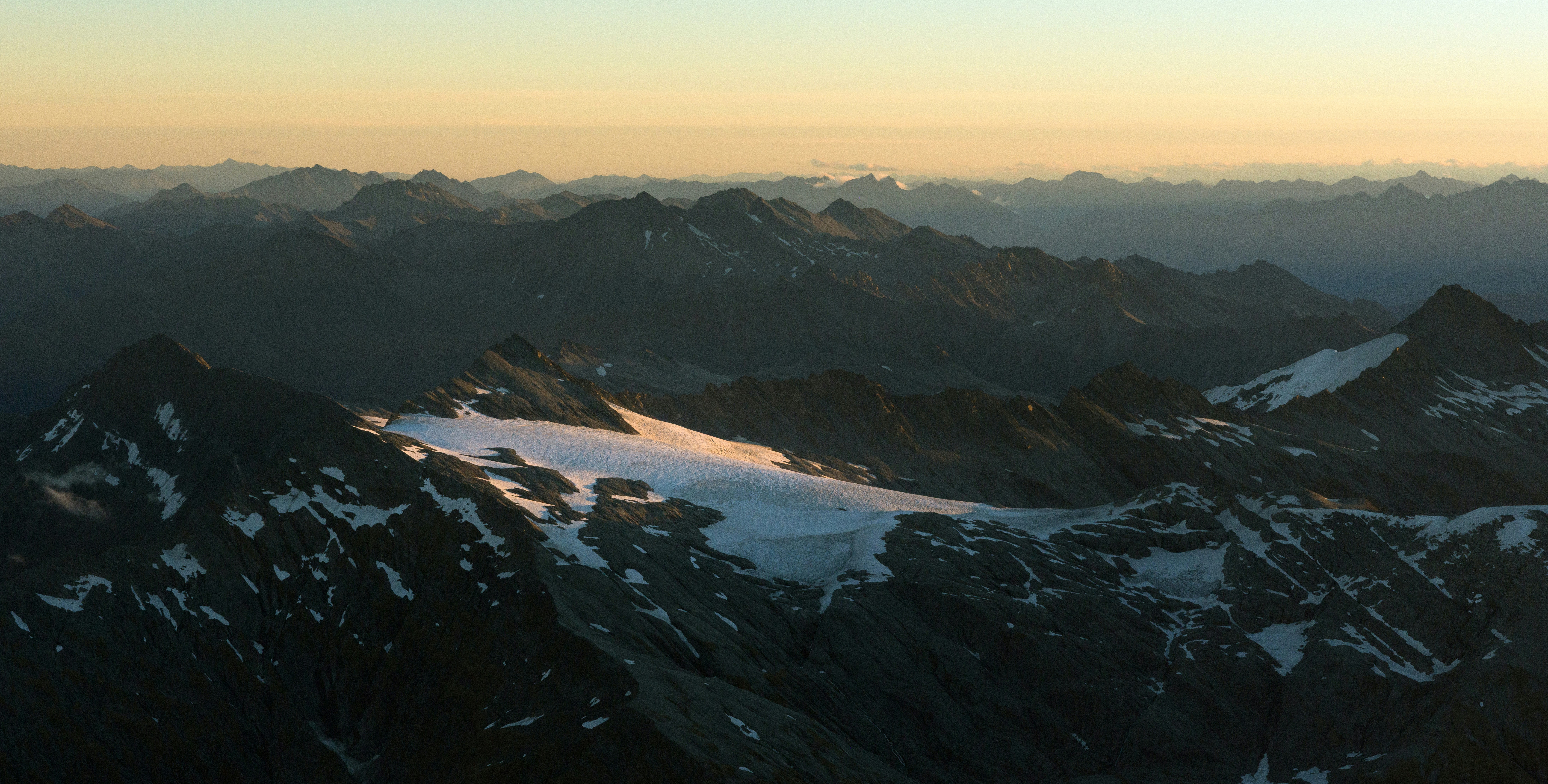 Snow-capped mountains under a hazy sunset sky