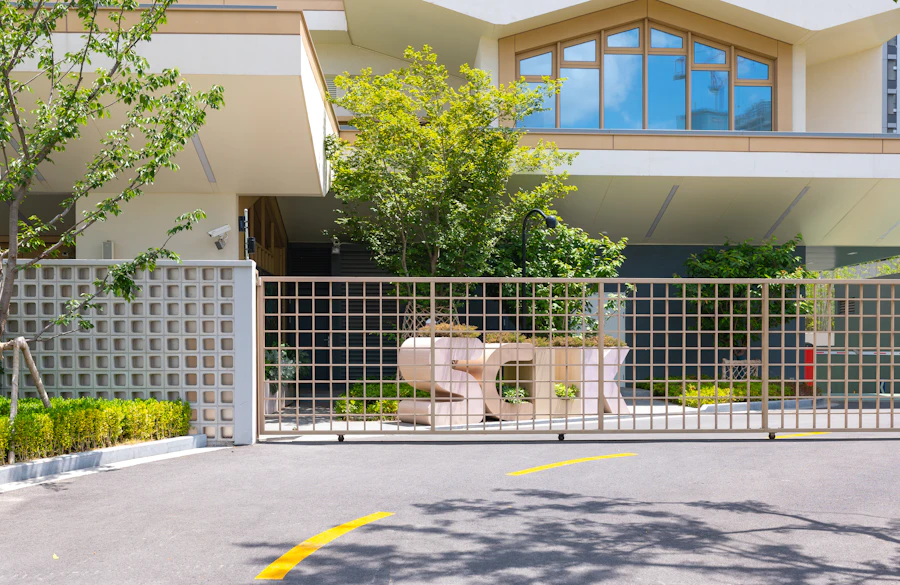 A modern house behind a closed metal gate with trimmed hedges.