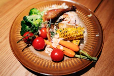 Roasted chicken with rice and fresh vegetables on a plate