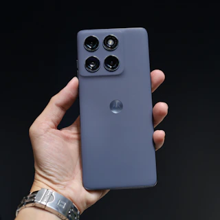 Hand holding a dark purple smartphone with four cameras.