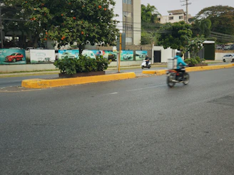 Motorcyclist rides down a wet city street.