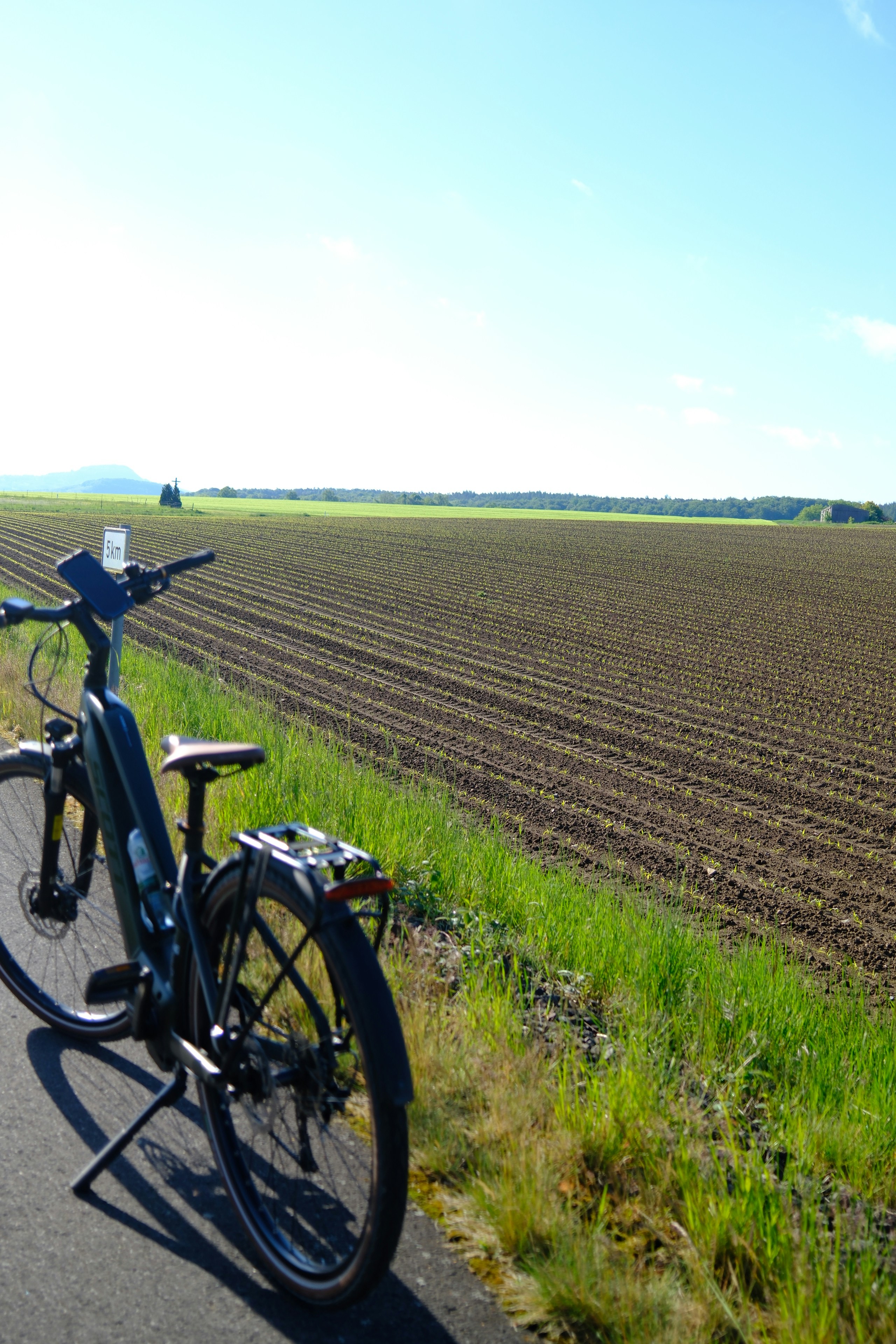 An electric bicycle parked on a road beside a field.