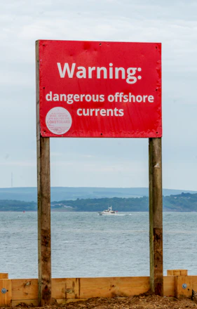 Red warning sign for dangerous offshore currents near a boat
