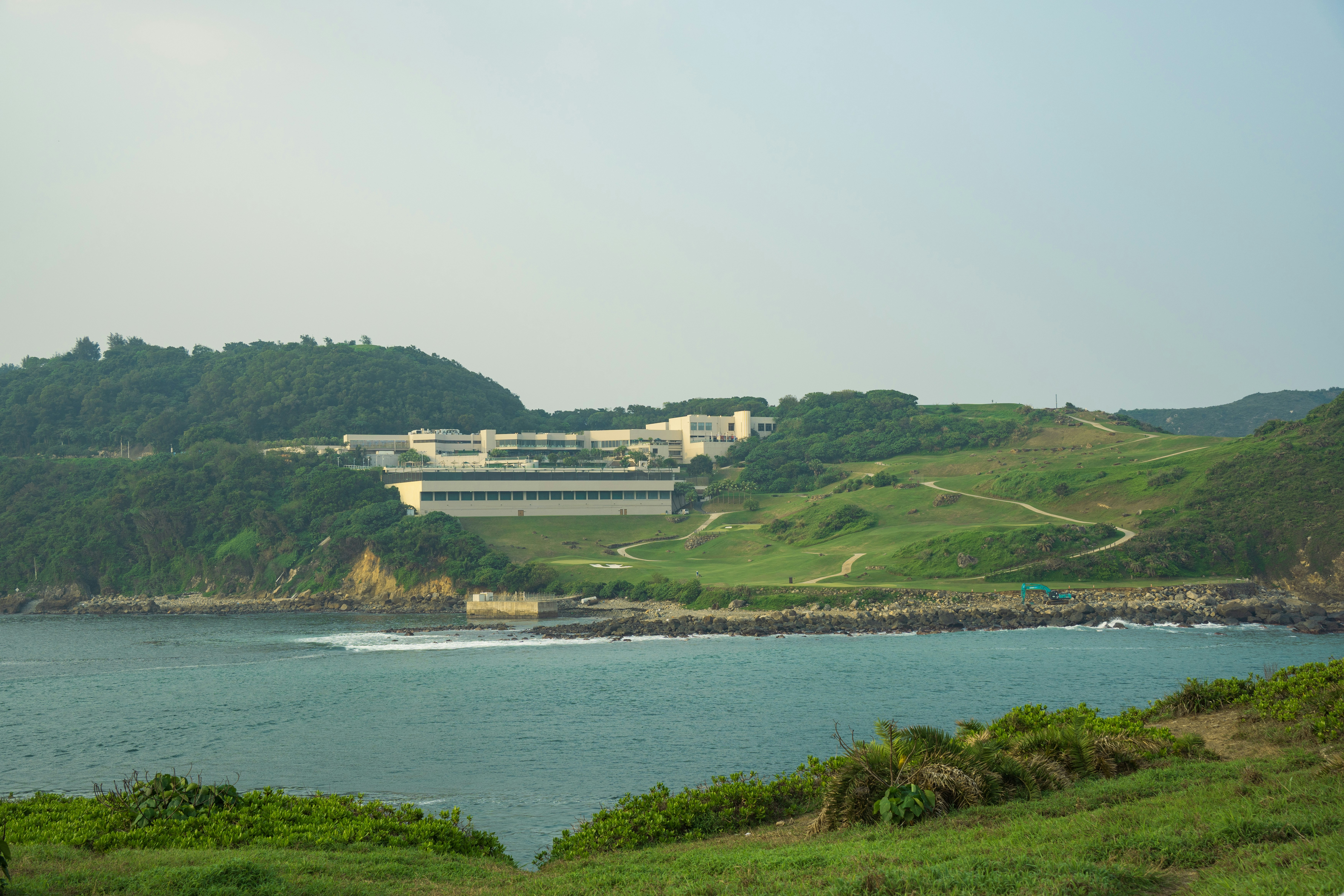 Ocean bay with buildings nestled on lush green hills.