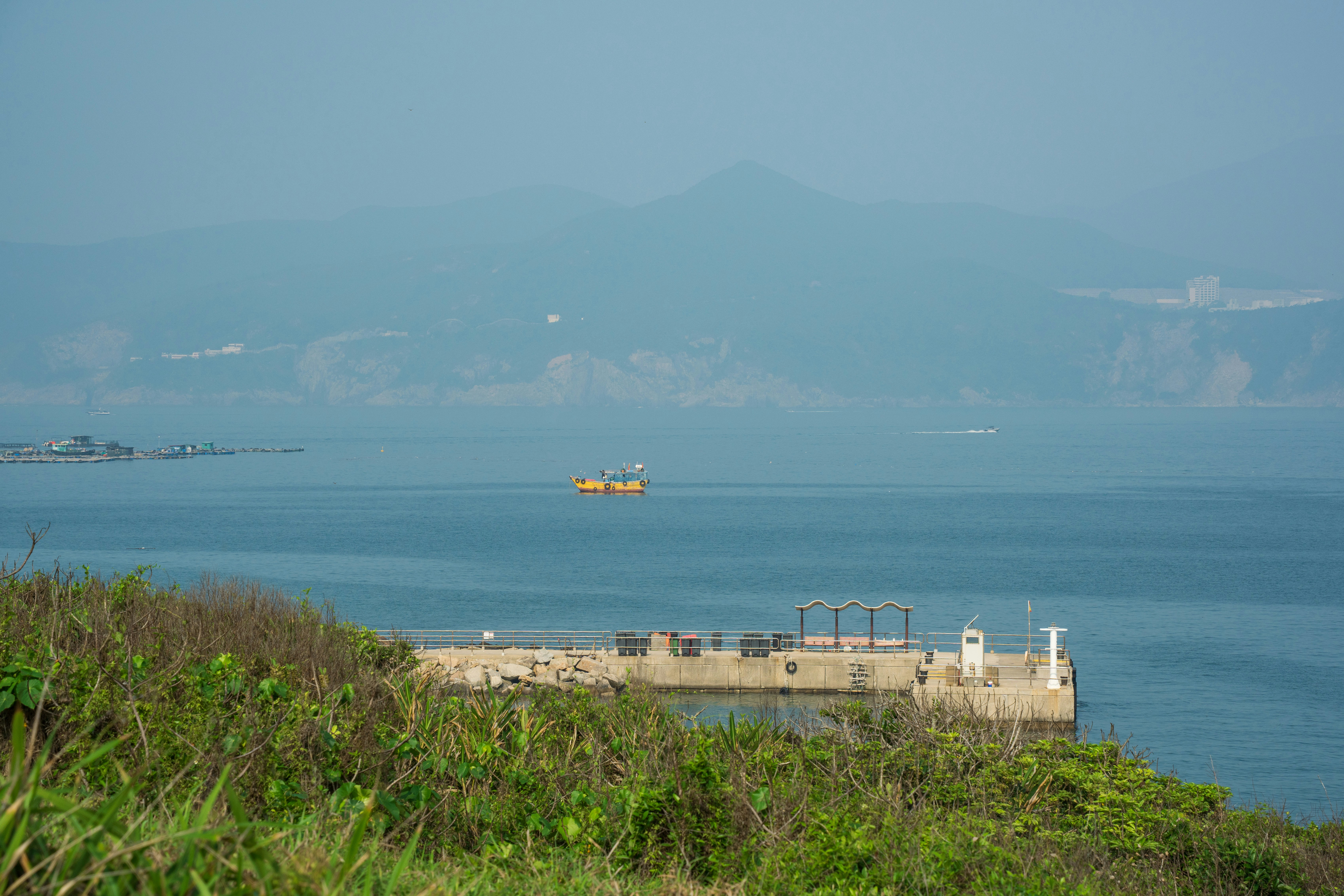 A small yellow boat sails on the calm sea.