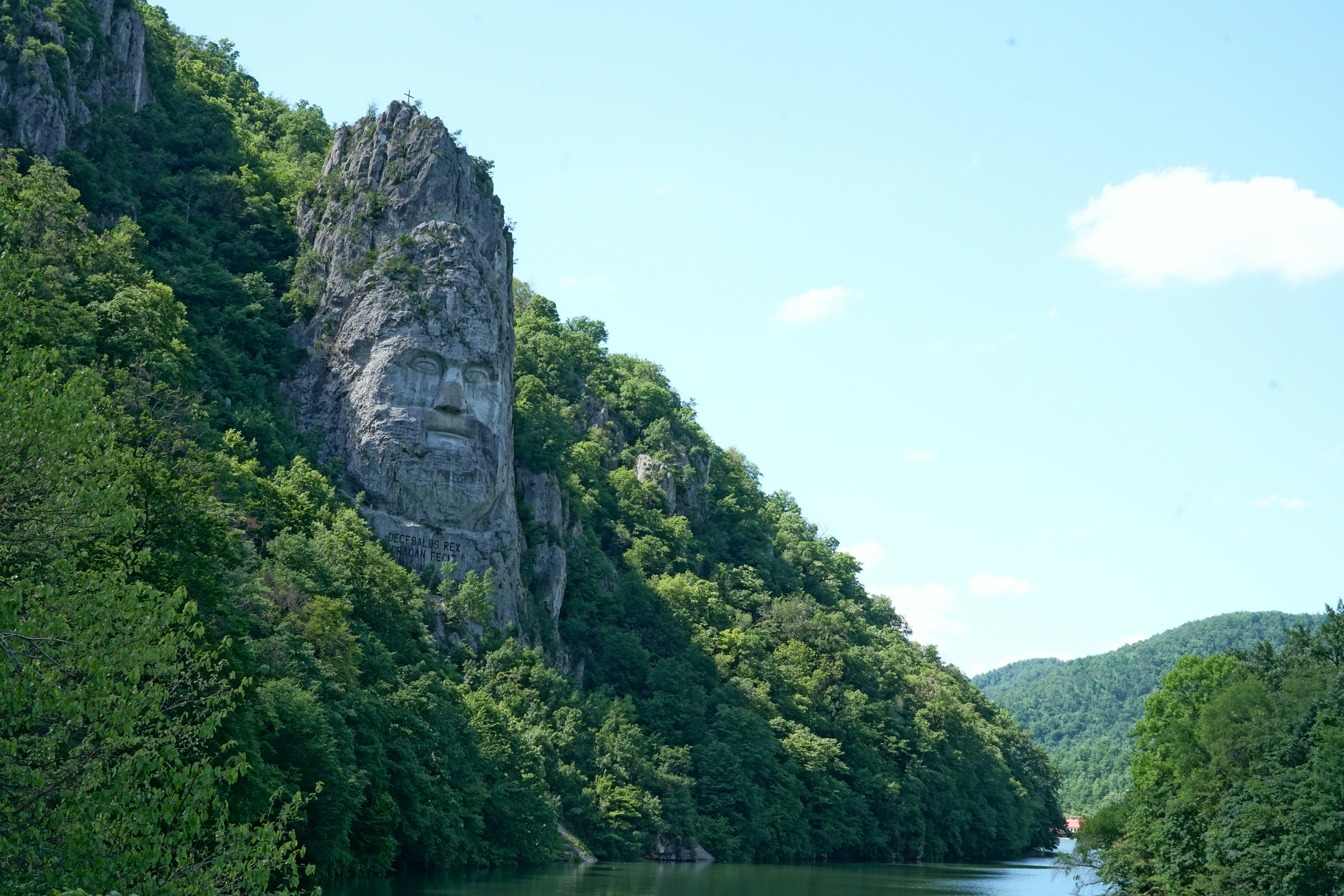 A dramatic rock face carved into a lush green mountainside.