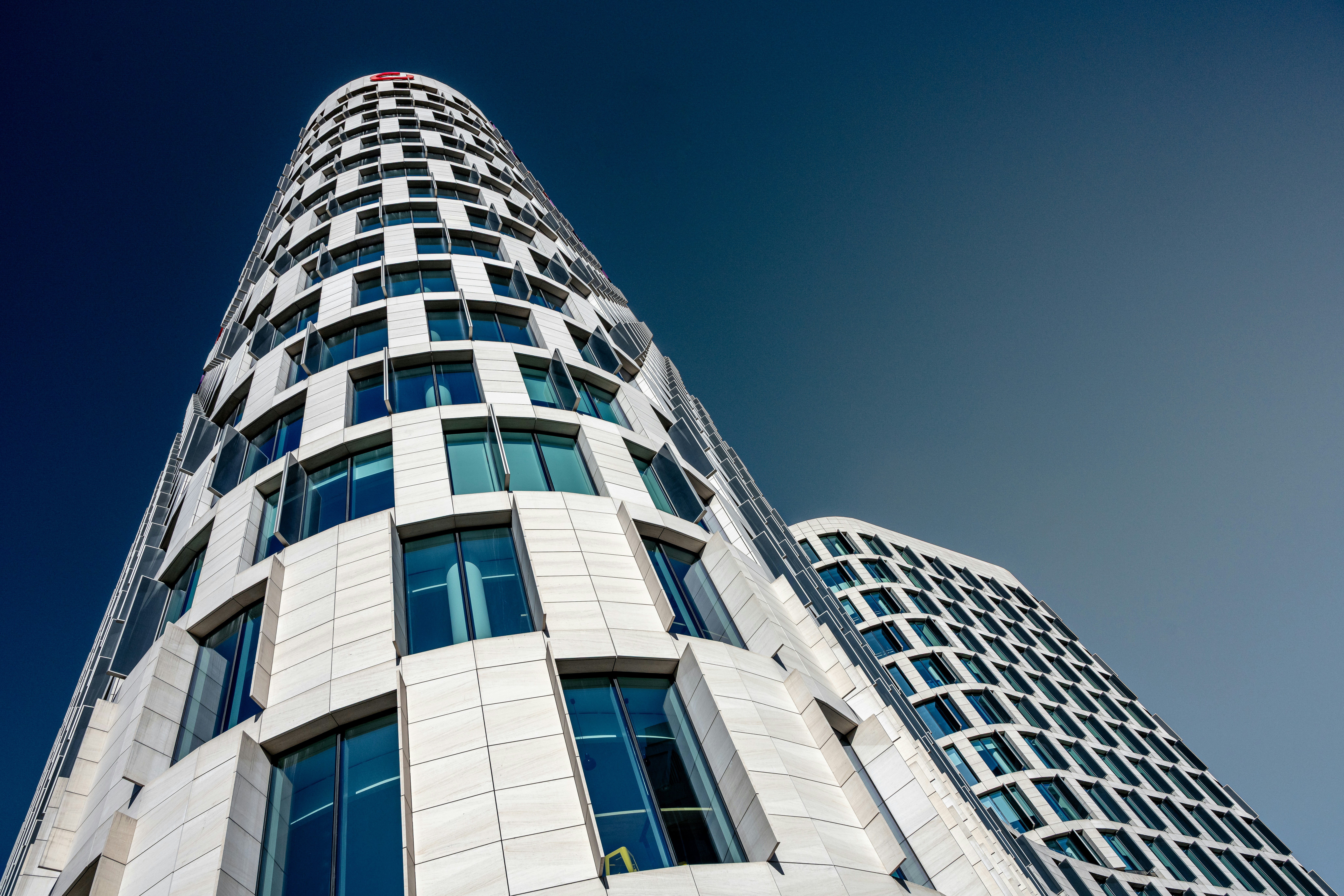 Tall modern building with many windows against a blue sky.