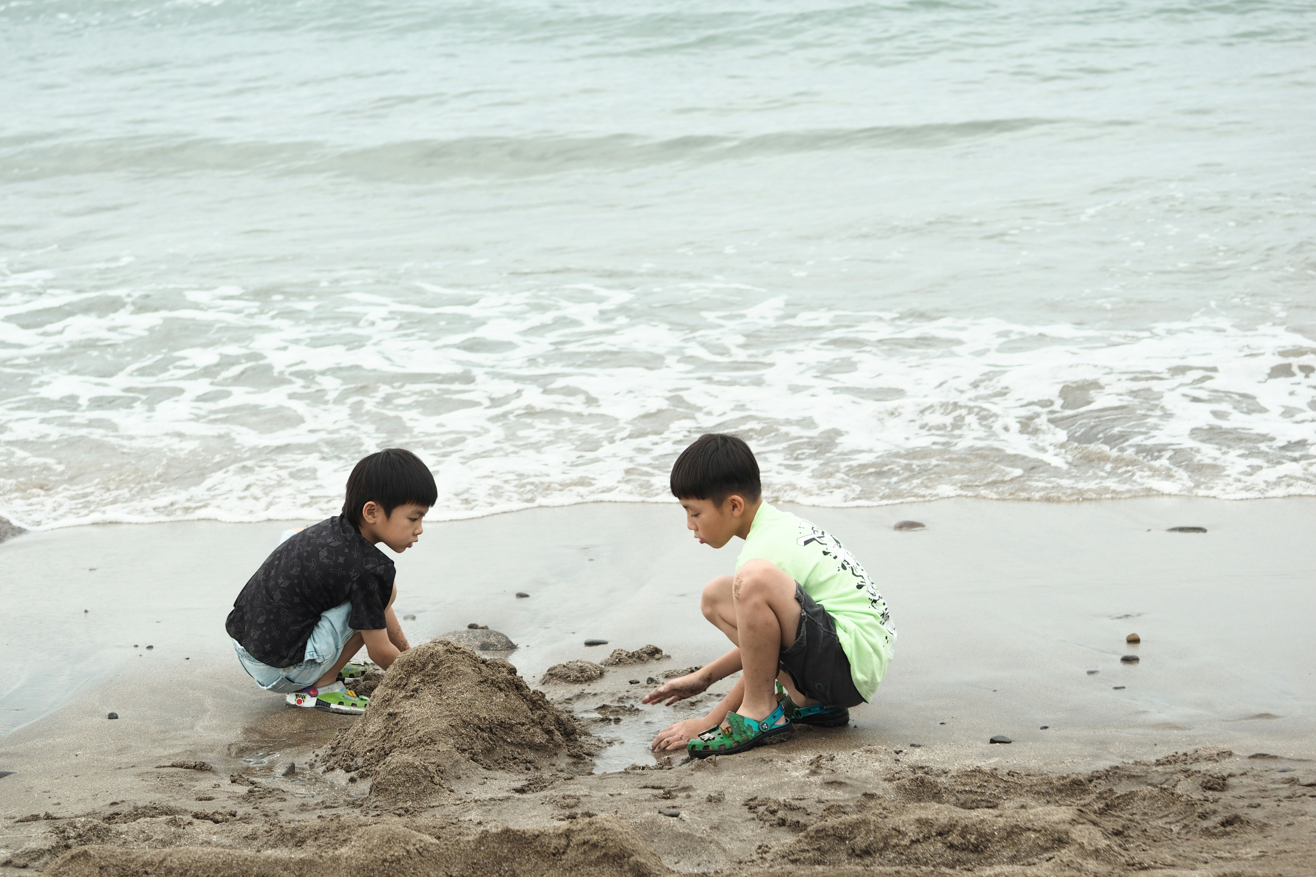 Dua anak laki-laki membangun istana pasir di pantai