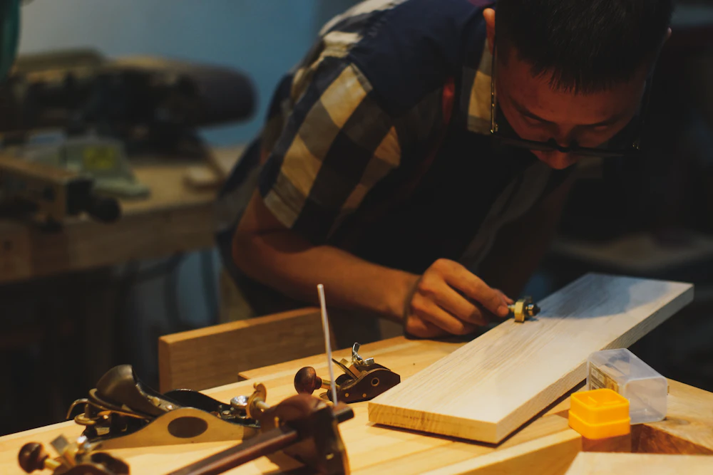 Craftsperson shaping wood by hand in a workshop