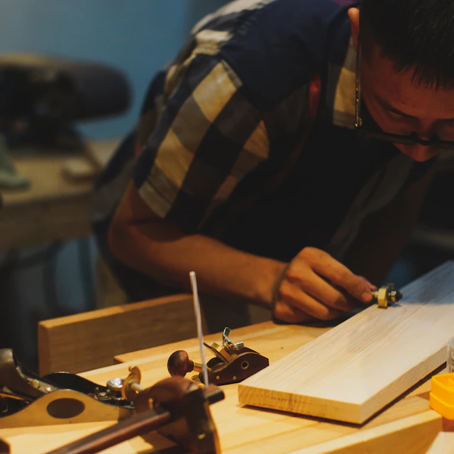 A carpenter working on wood with hand tools in a workshop