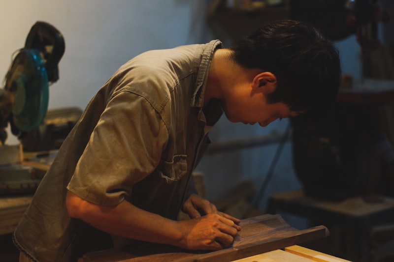Thợ trẻ cẩn thận chà nhám gỗ trong xưởng – Nội Thất Vương Quốc Trảng Bàng
