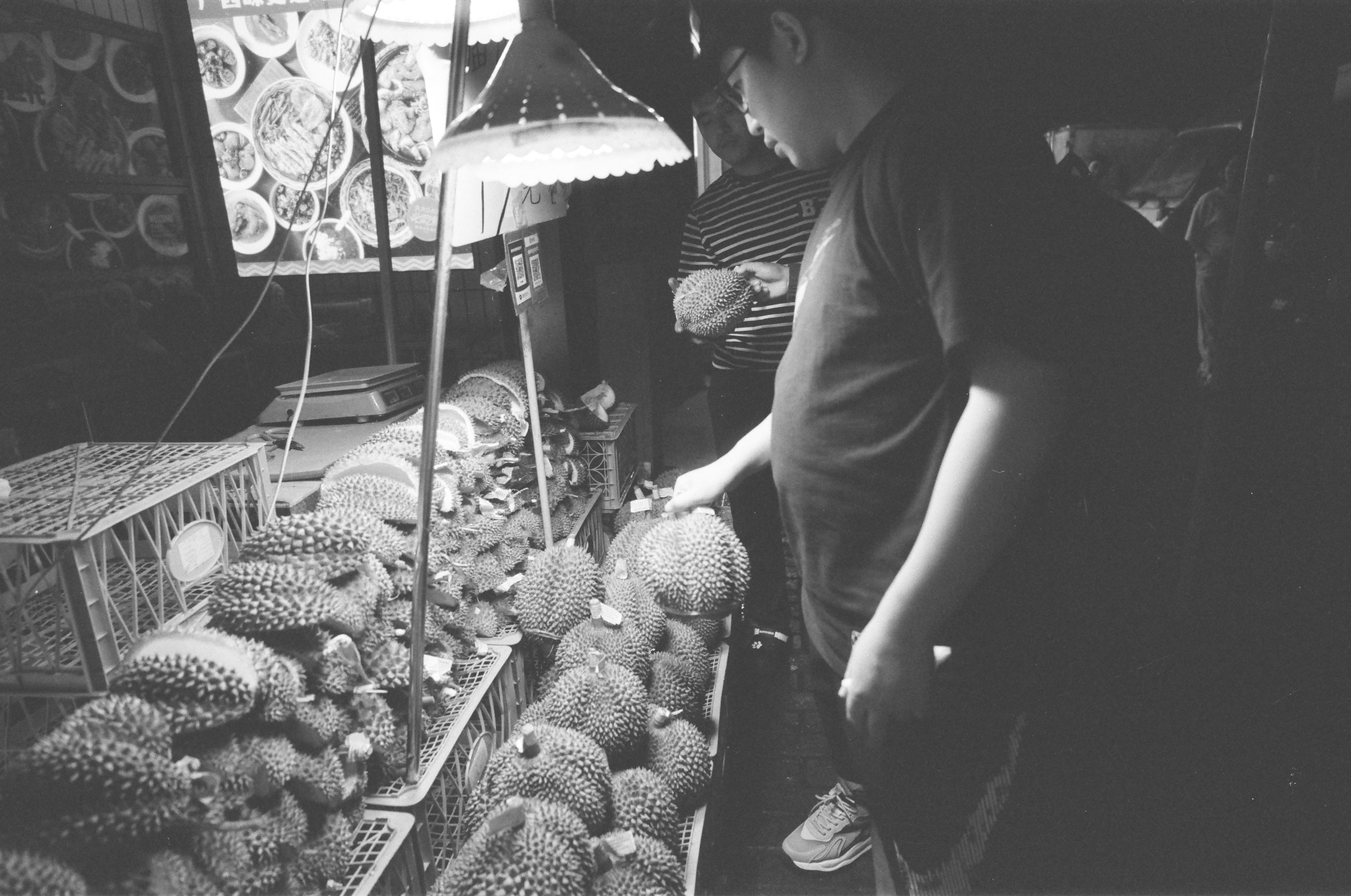 Man selecting durians at a market stall