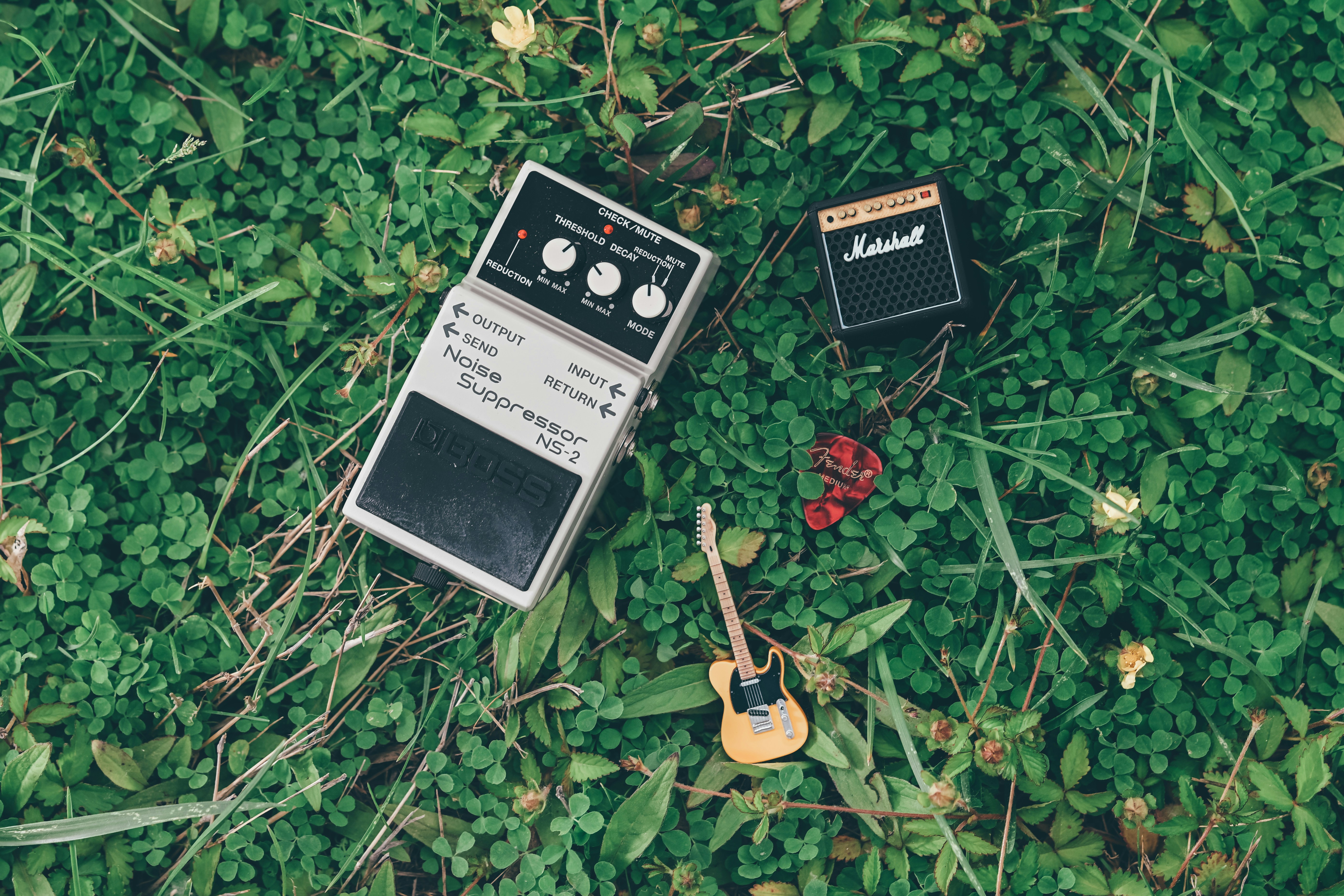 Gitar mini, amplifier, dan pedal efek di atas rumput