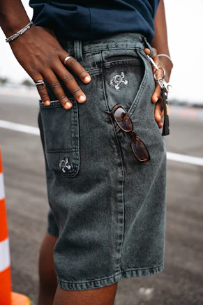 Person wearing dark denim shorts with sunglasses in pocket.