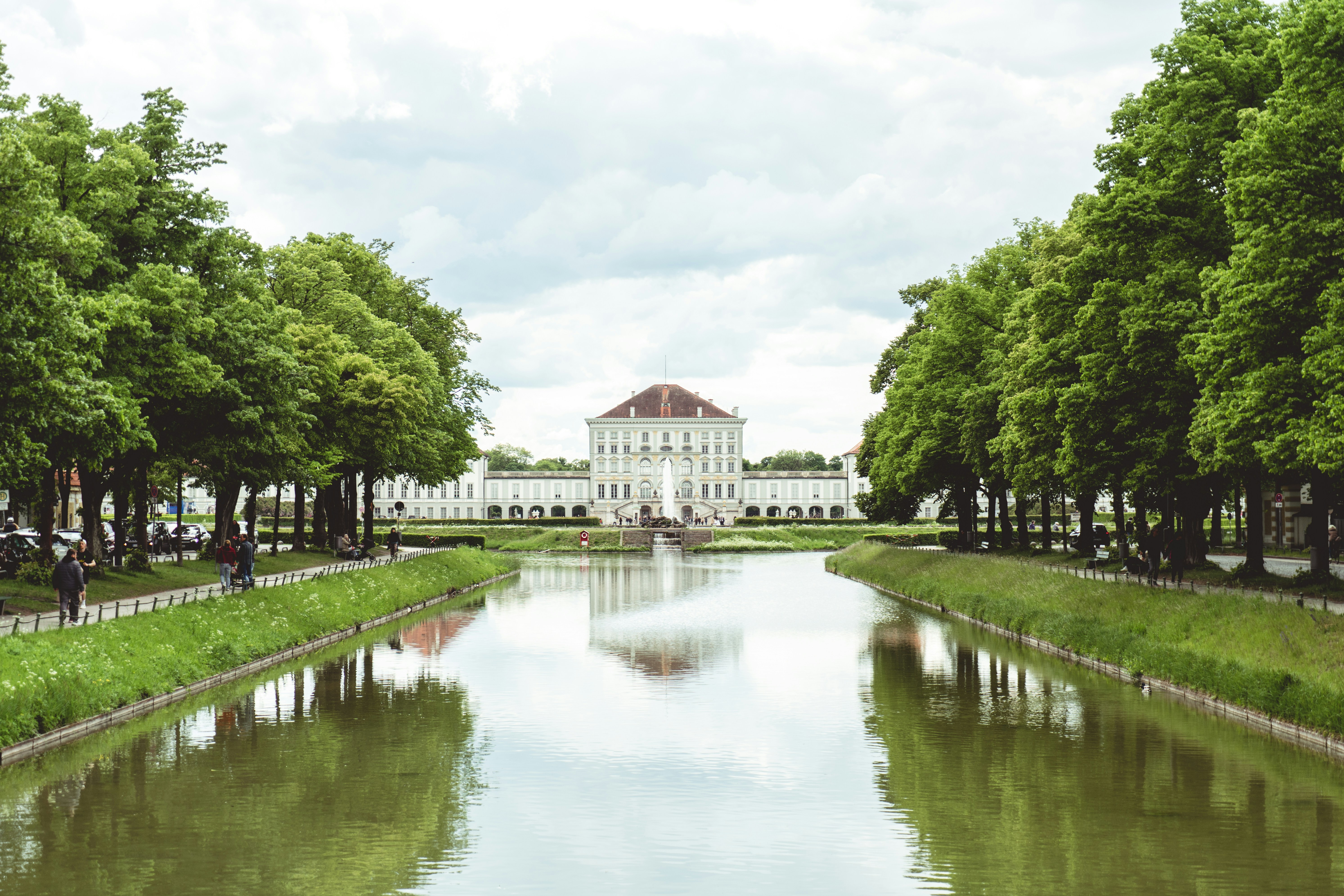 The tree-lined canal avenue leading to the white facade of Schloss Nymphenburg in Munich
