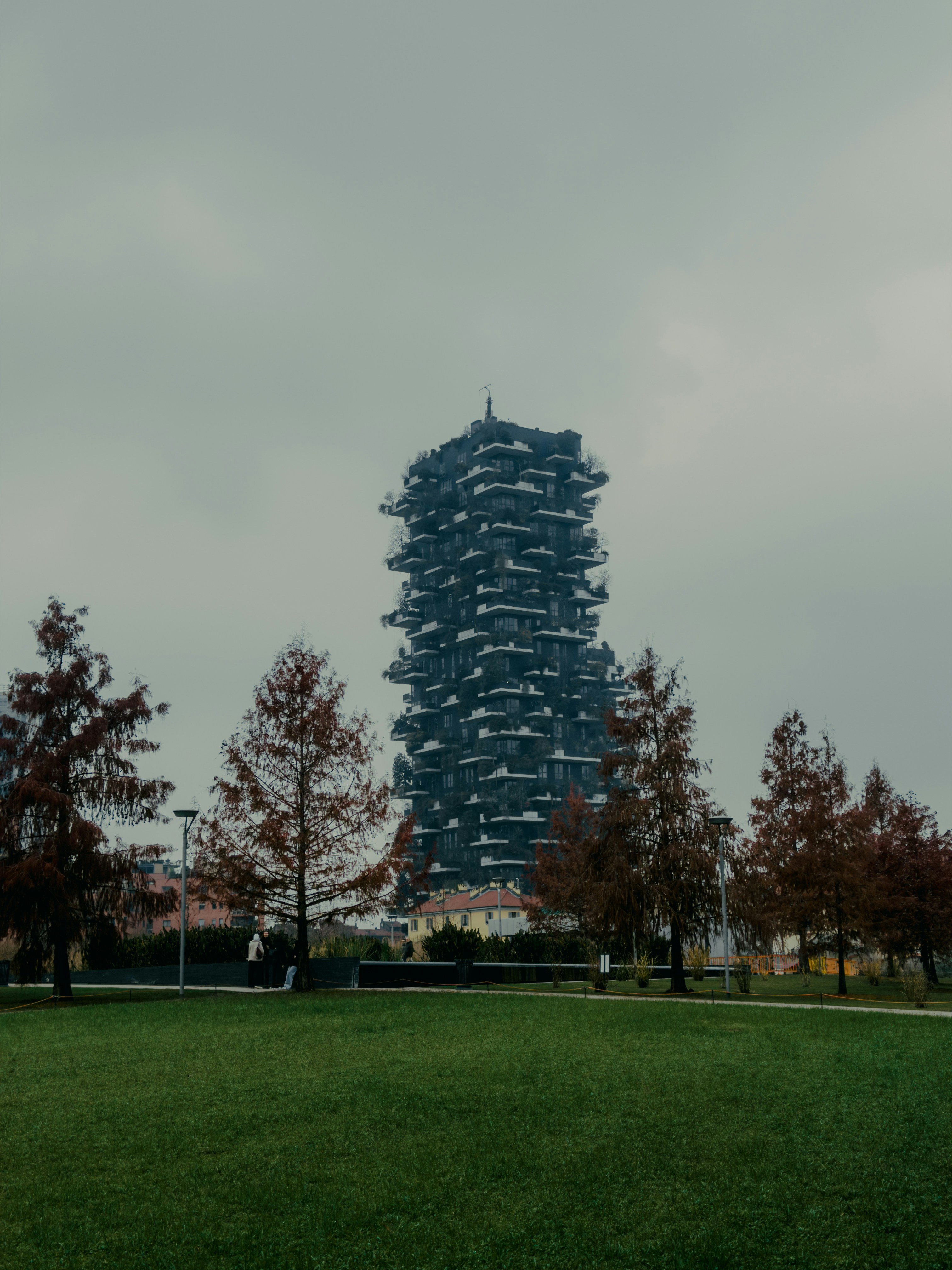 Modern skyscraper with trees in foreground on a cloudy day