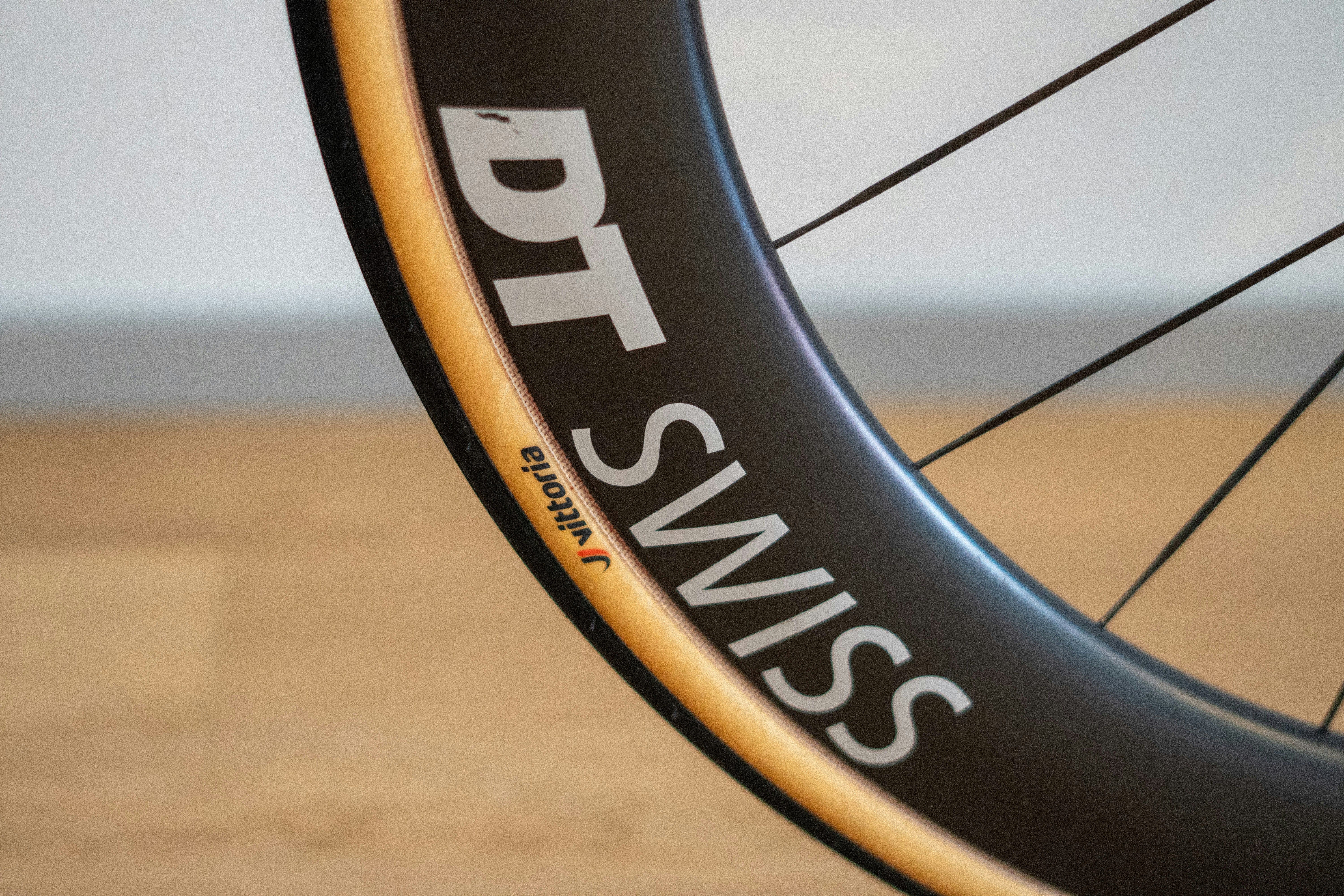 Black bicycle wheel with "dt swiss" logo and tan sidewall.