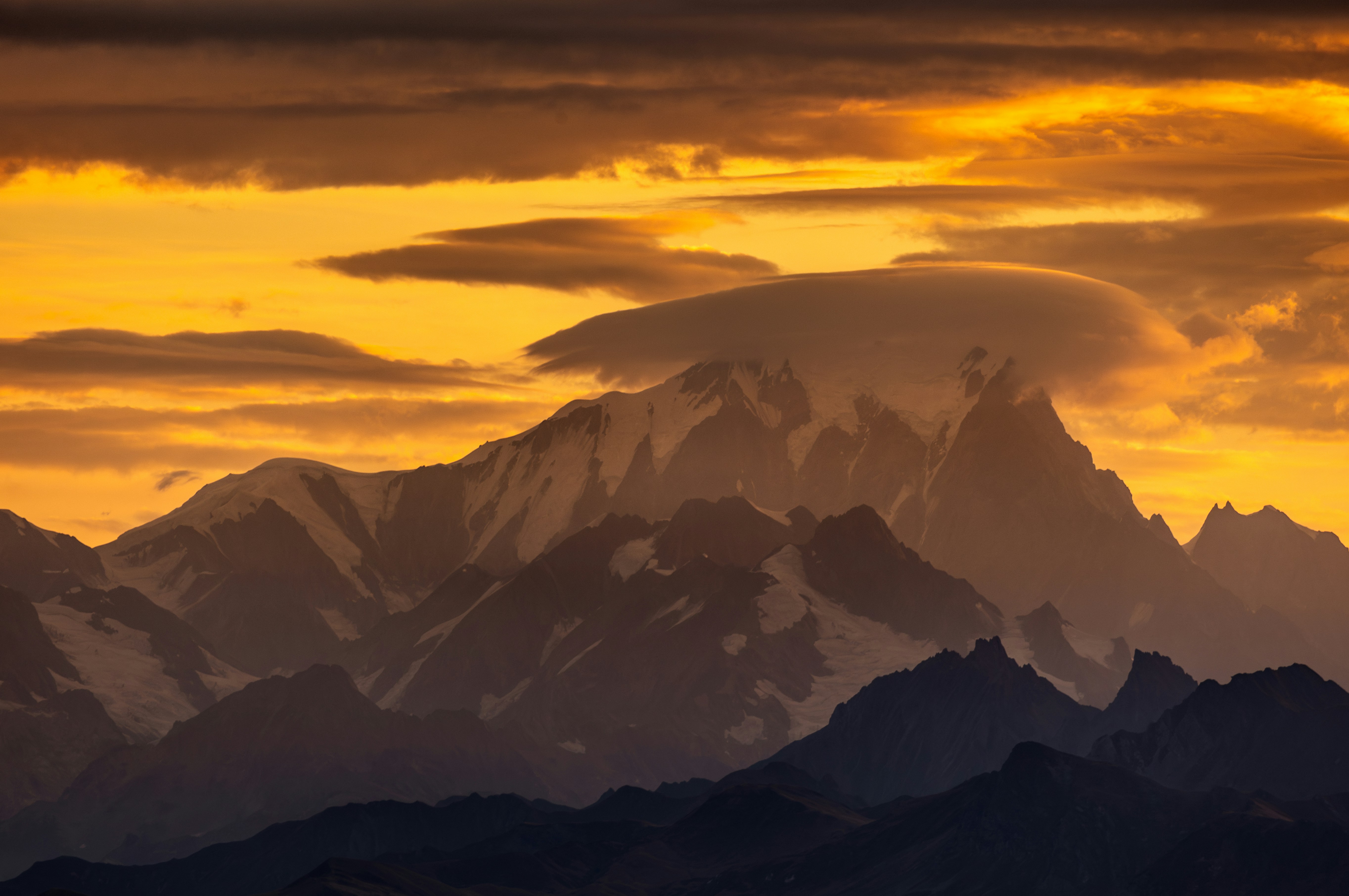 Majestic mountain range under a dramatic golden sunset sky.