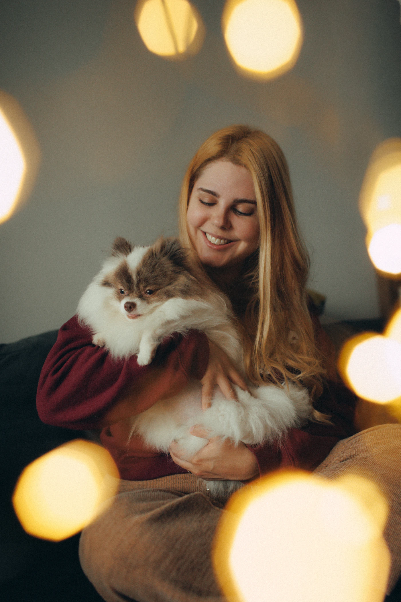 A smiling pet parent holding a fluffy dog in a cozy home