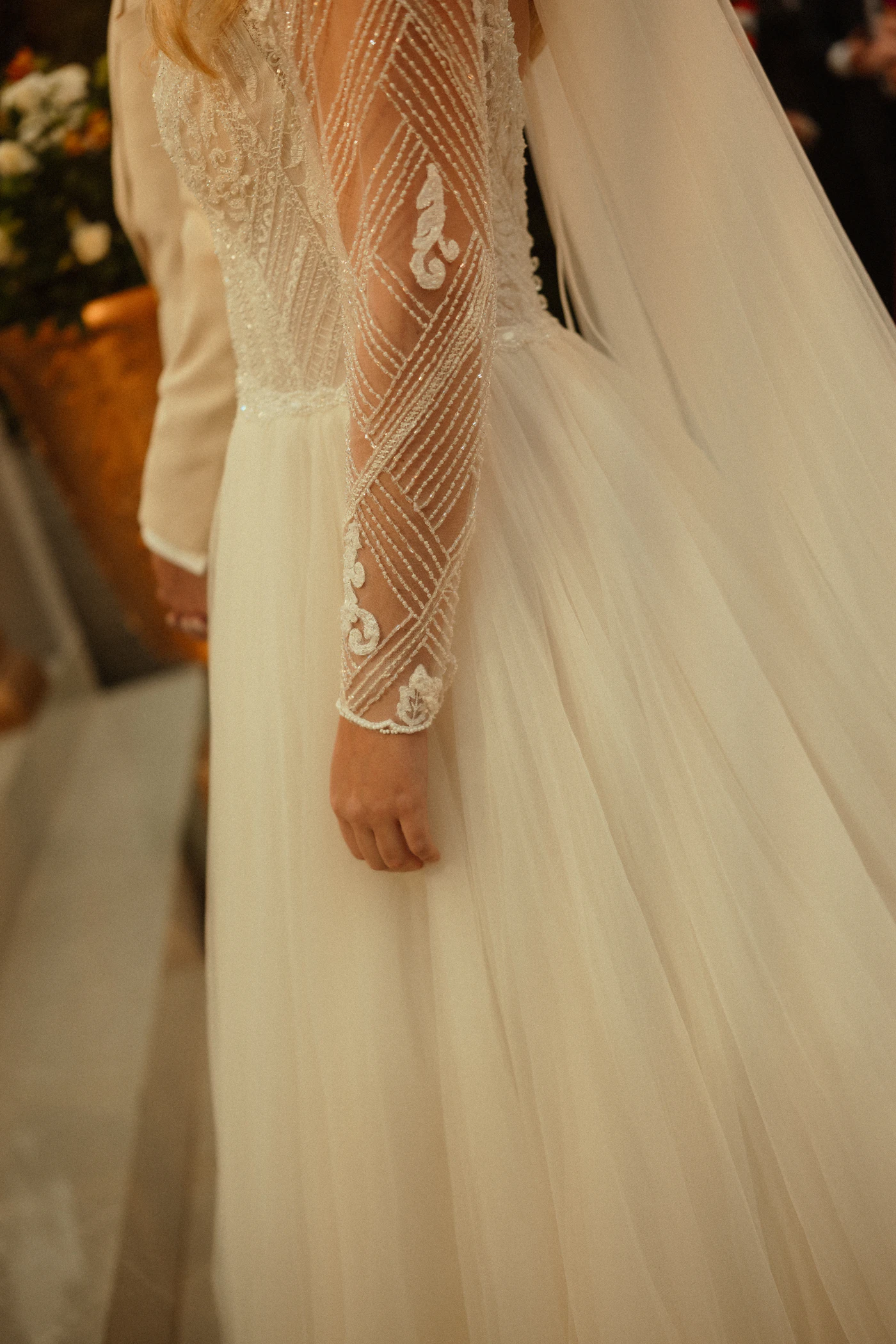 Modest wedding dress designs with long sleeves — A bride wearing a long-sleeved lace wedding dress with a high neckline.