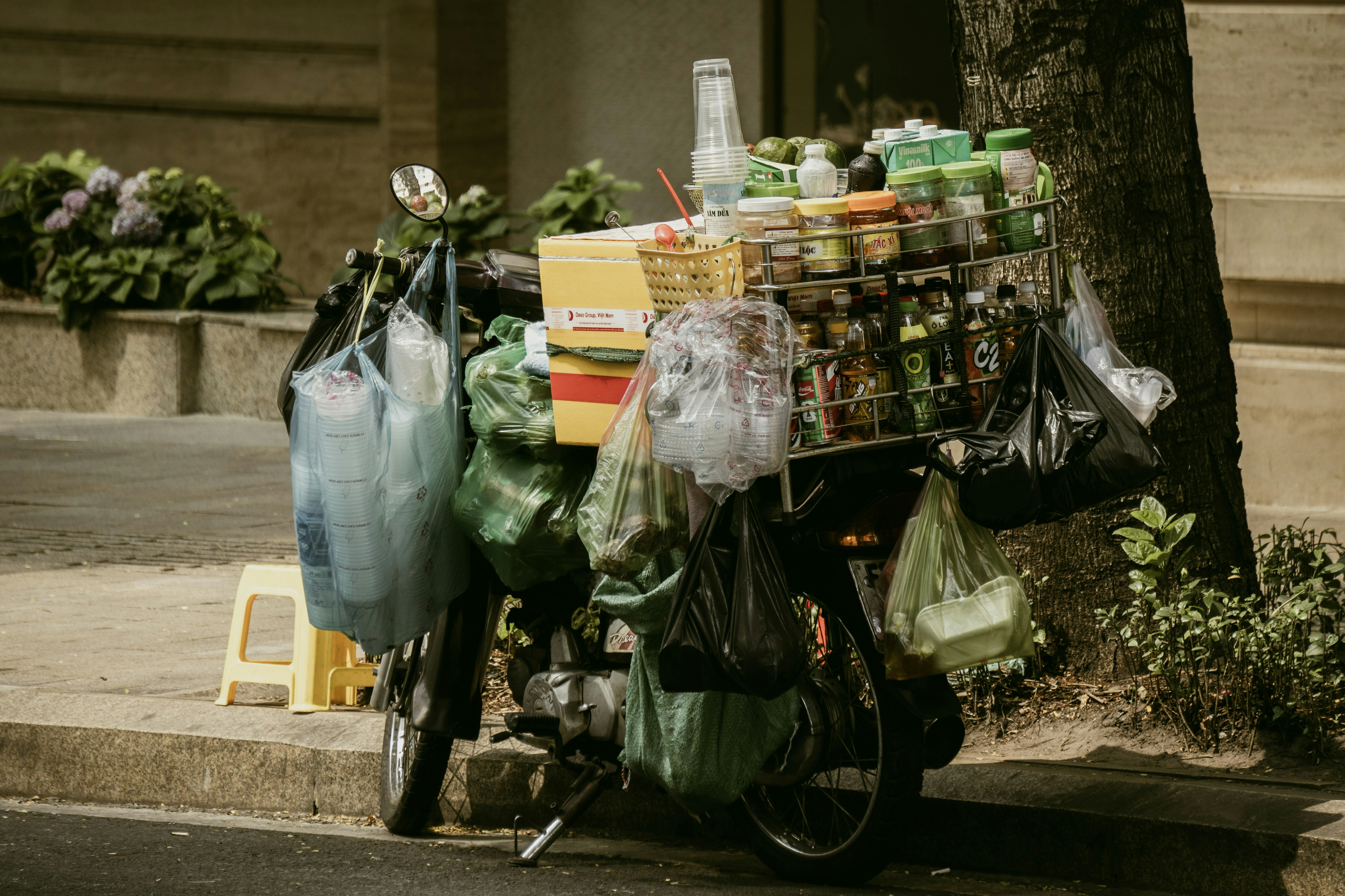 A motorcycle heavily loaded with various goods and plastic bags.
