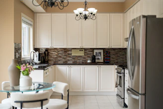 A modern kitchen with cream cabinets and stainless steel appliances.