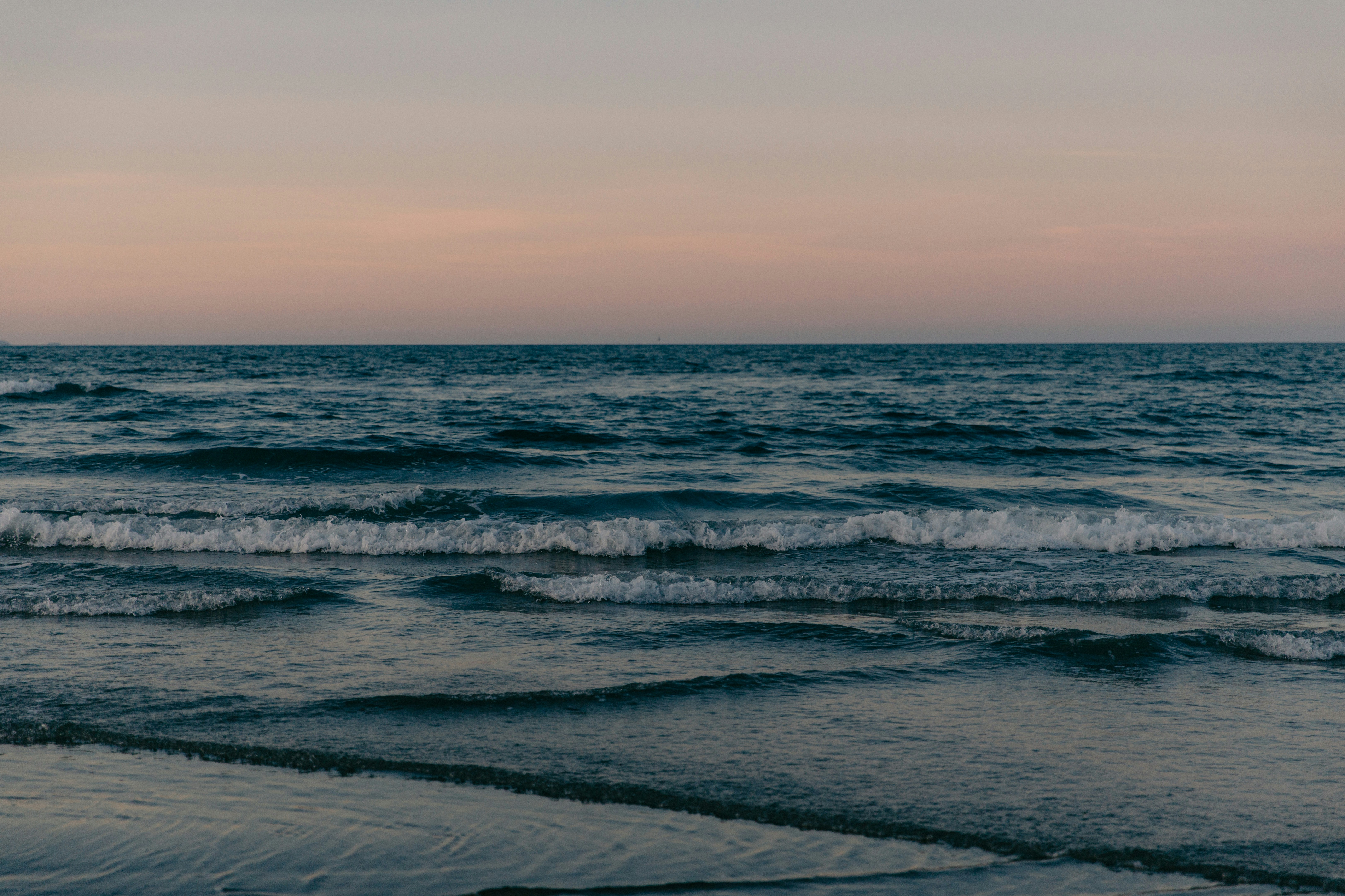 Gentle ocean waves wash ashore under a pastel sky. - 相关推荐