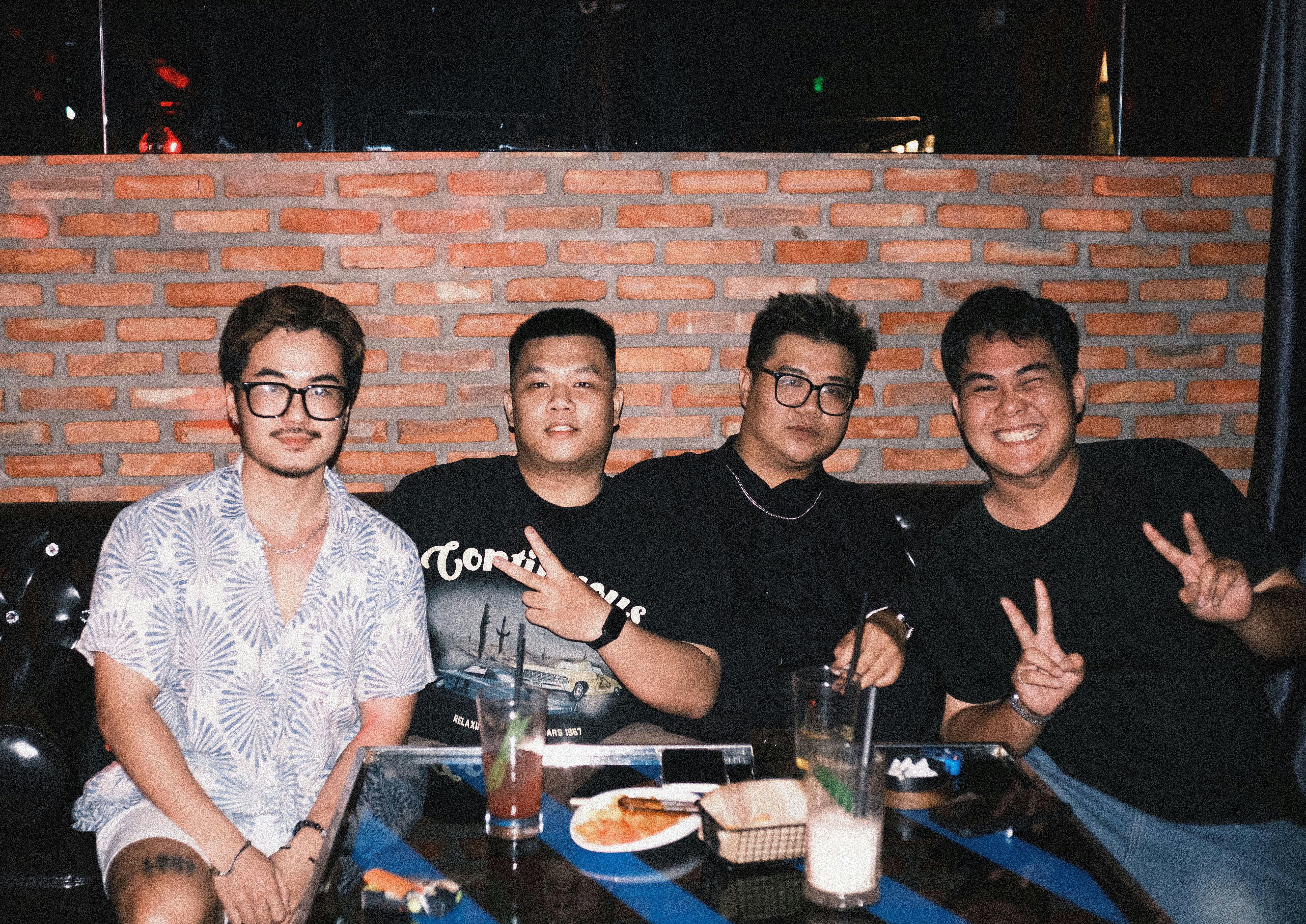 Empat pemuda bersosialisasi di sebuah meja di sebuah bar.