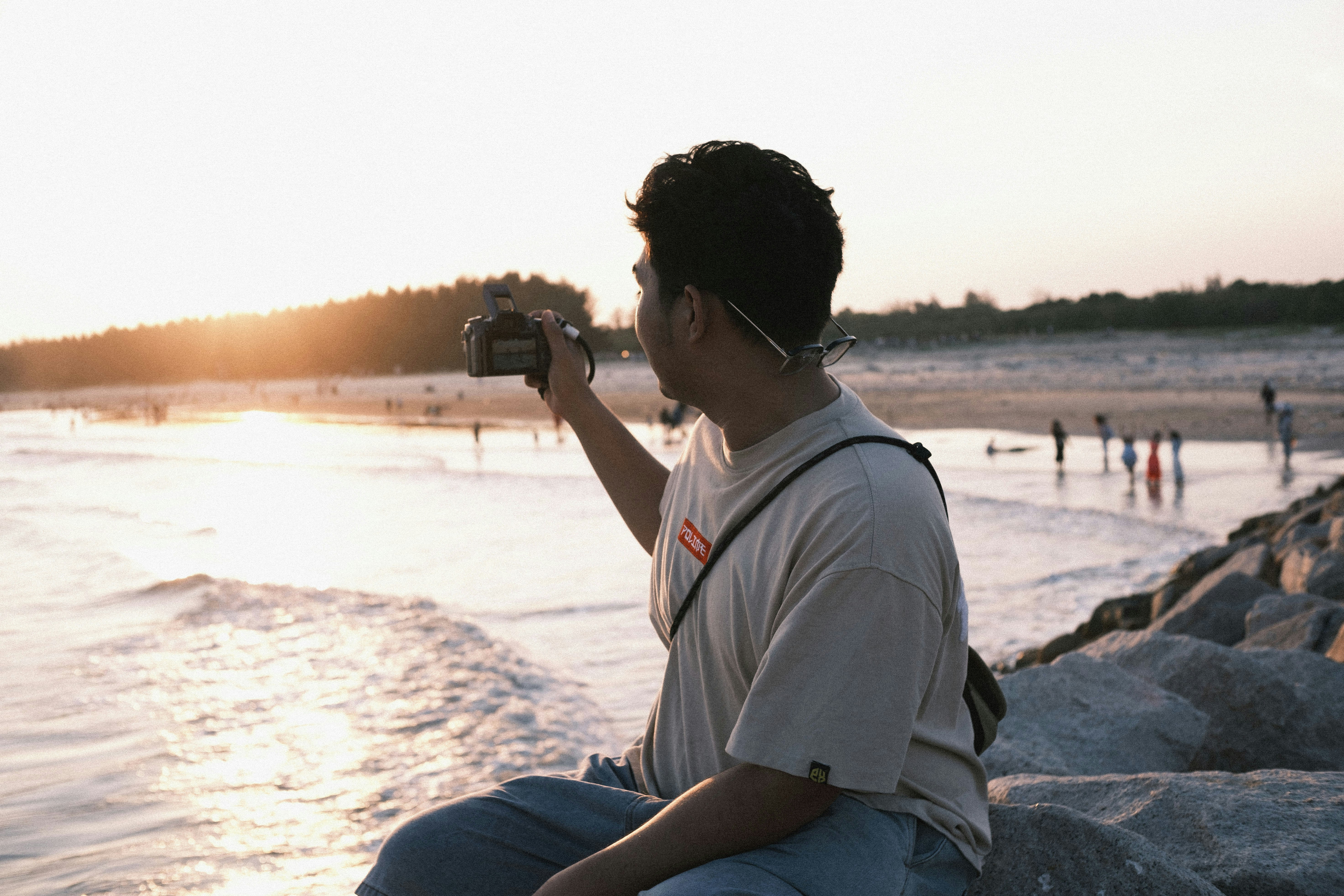 Young man filming sunset on a beach