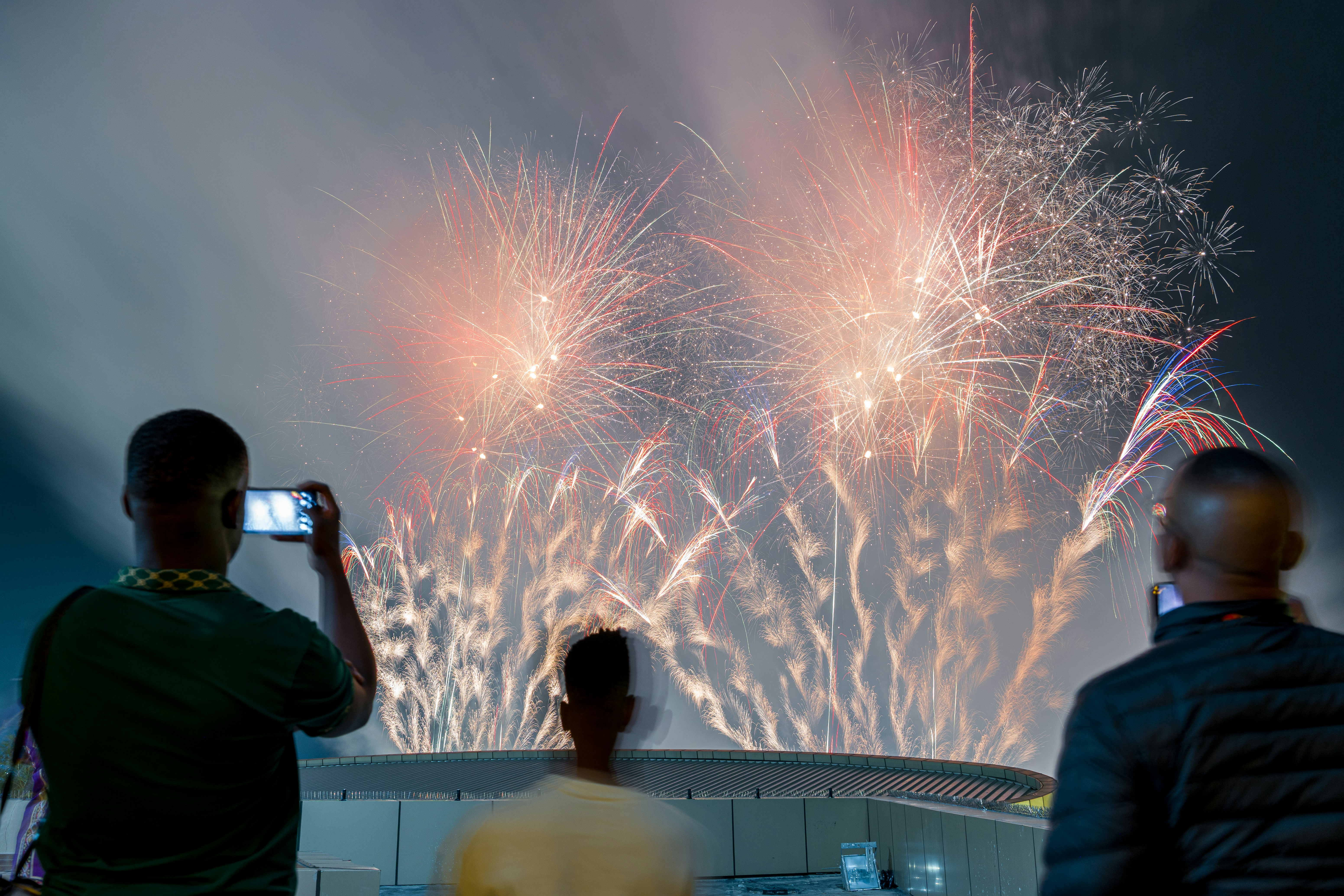 Die Leute beobachten, wie nachts Feuerwerke über einem Stadion explodieren.