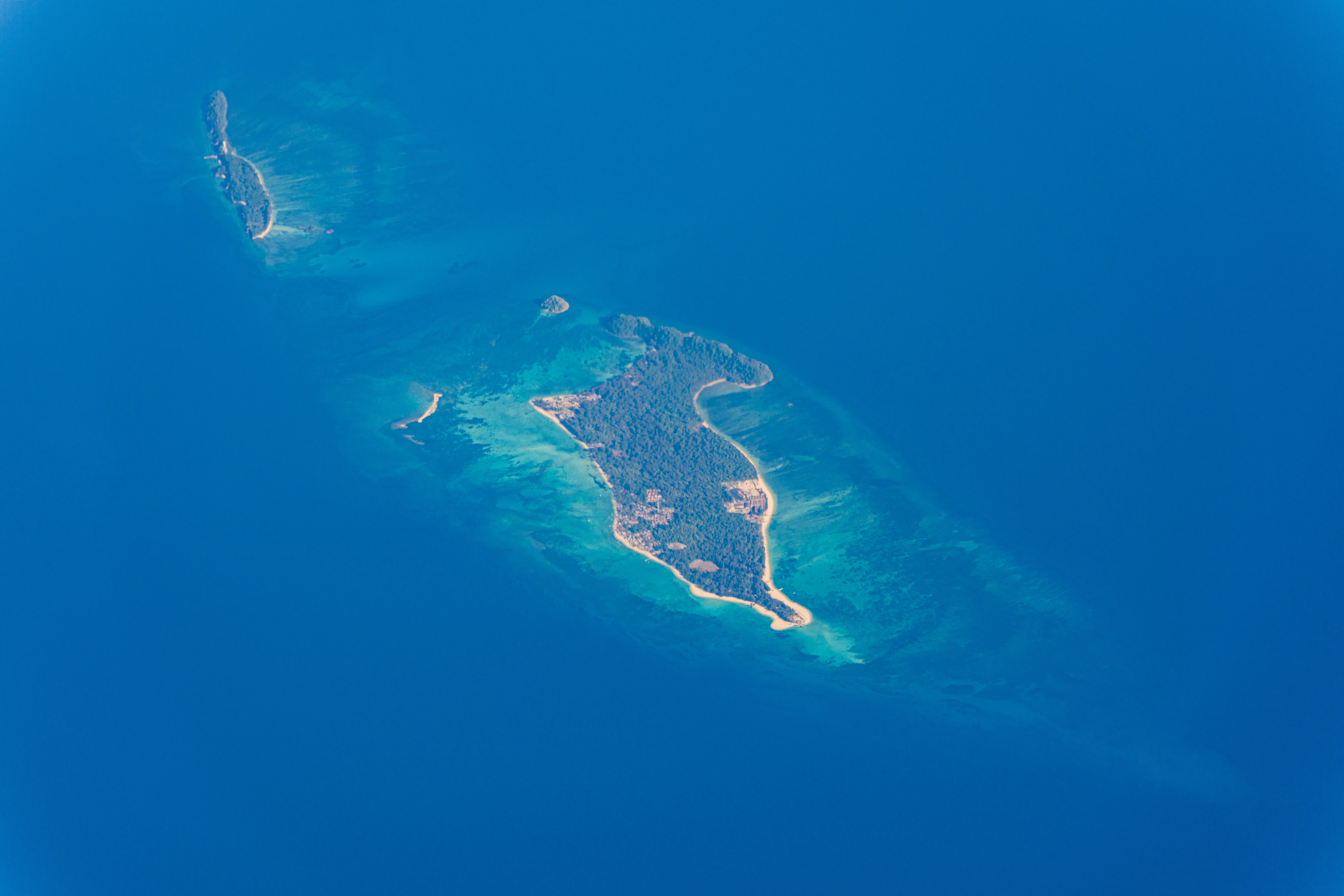 Luftaufnahme einer tropischen Insel, umgeben von blauem Ozean.