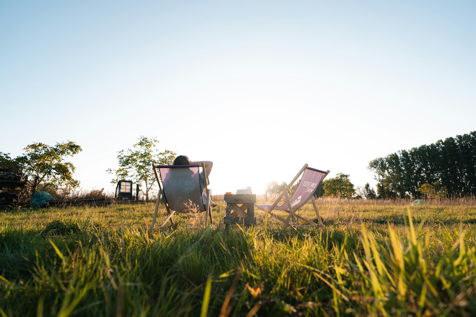 Person relaxing in a chair in a sunny grassy field