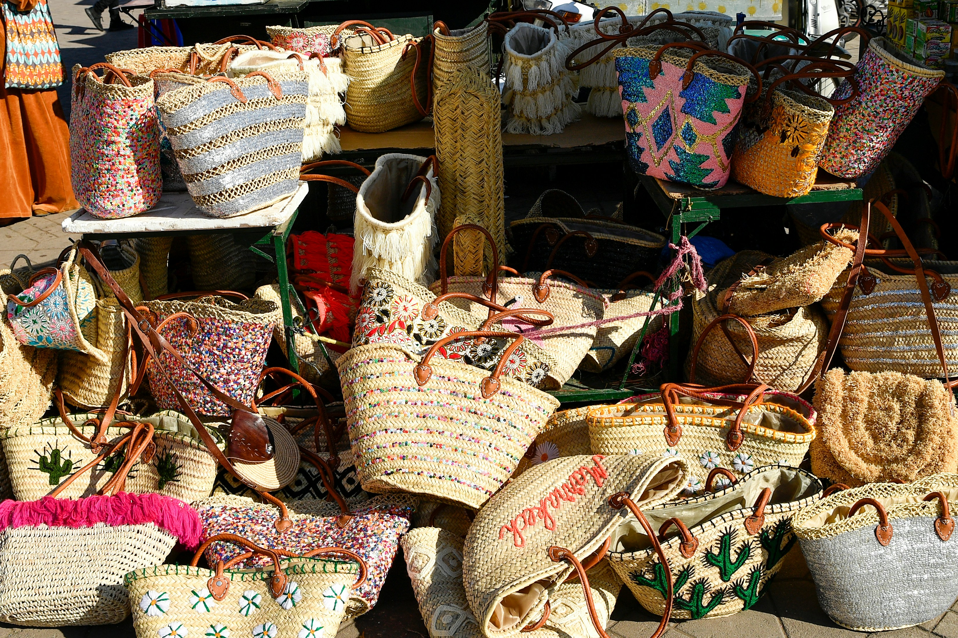 A display of many woven straw bags with colorful designs.