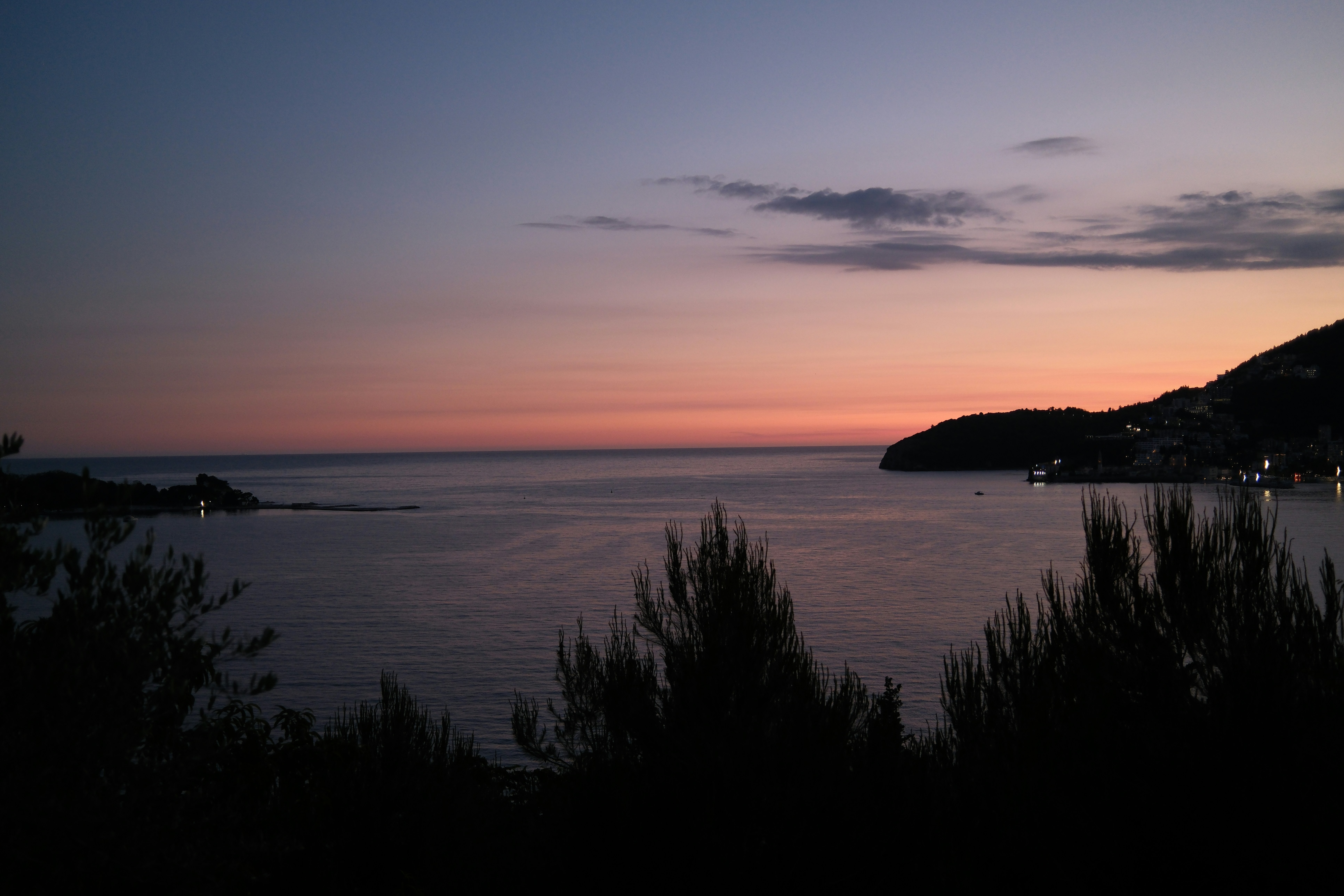 Ciel crépusculaire violet et orange au-dessus d’un océan calme.