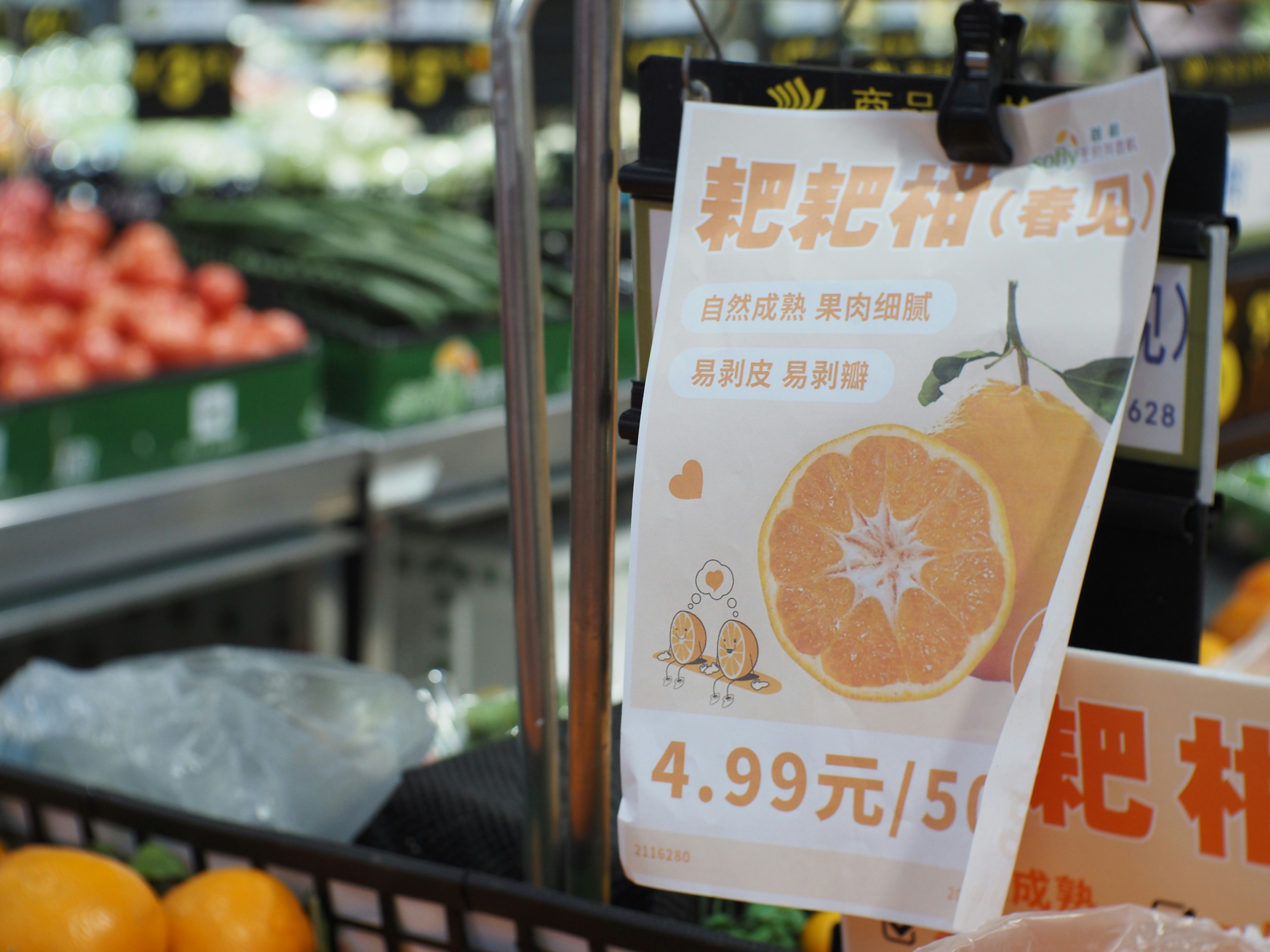Supermarket sign displaying oranges and price in a produce aisle.