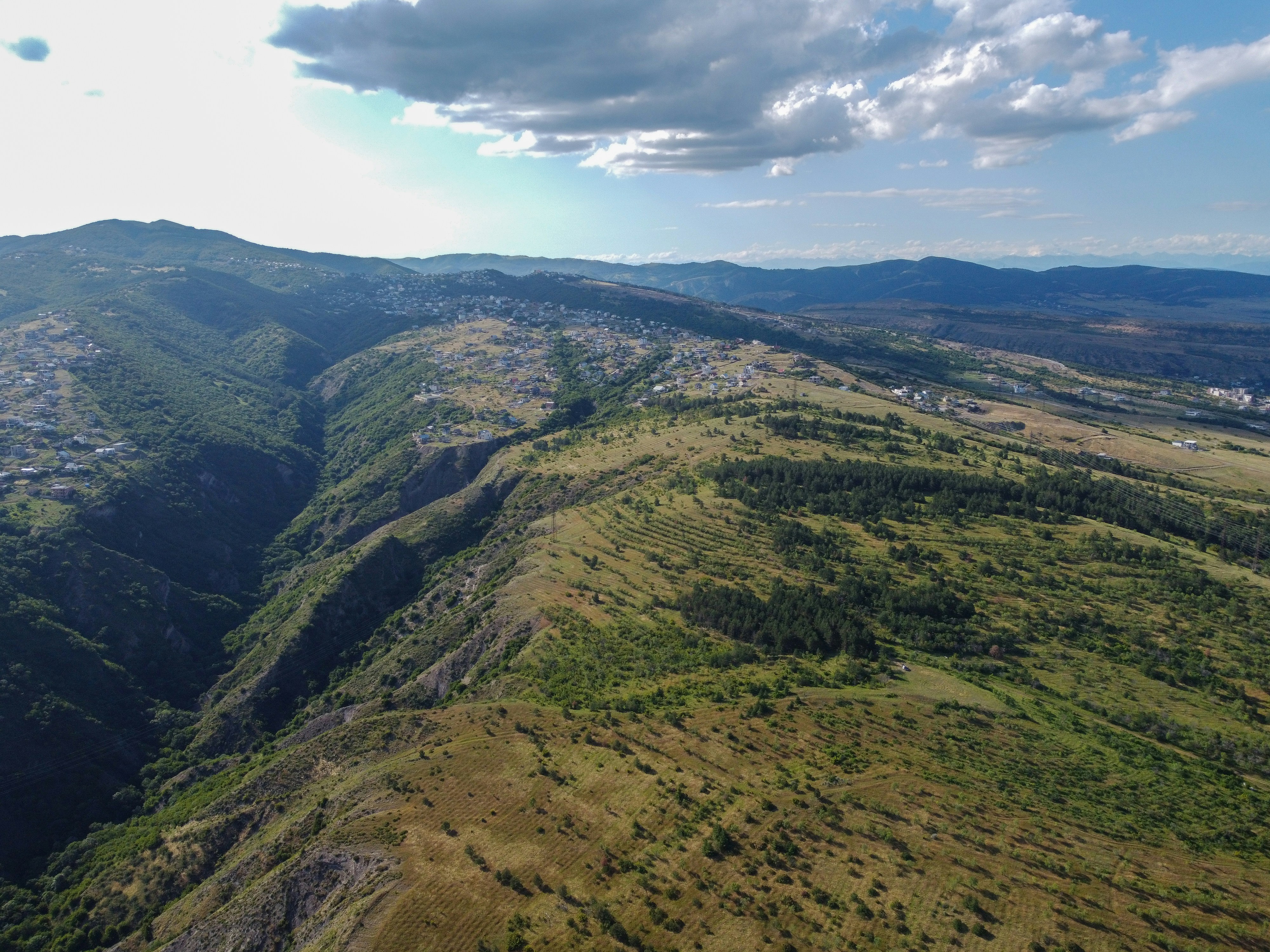 Aerial view of green mountains, valleys, and distant towns.