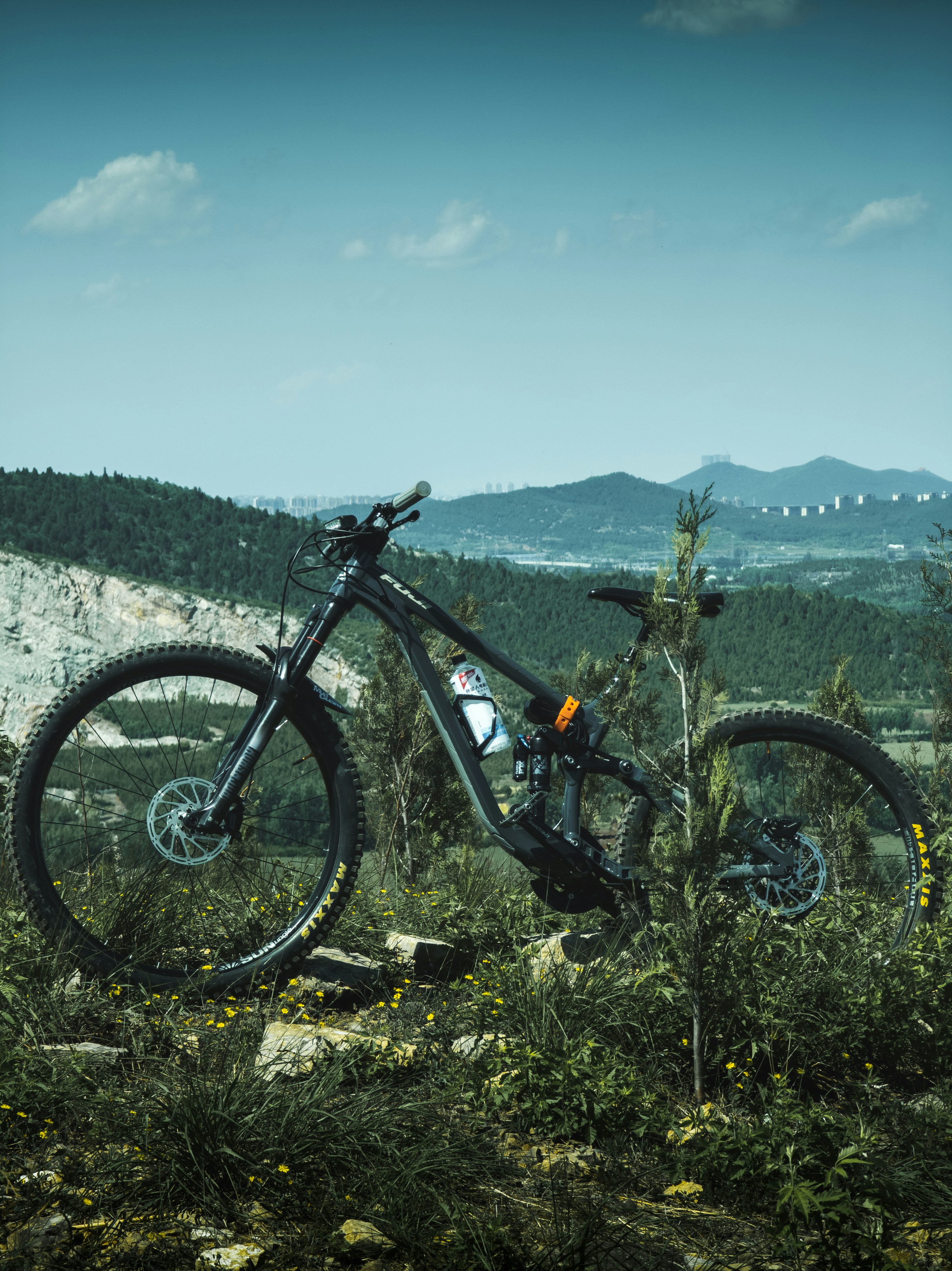 Black mountain bike on a hill with a distant town.