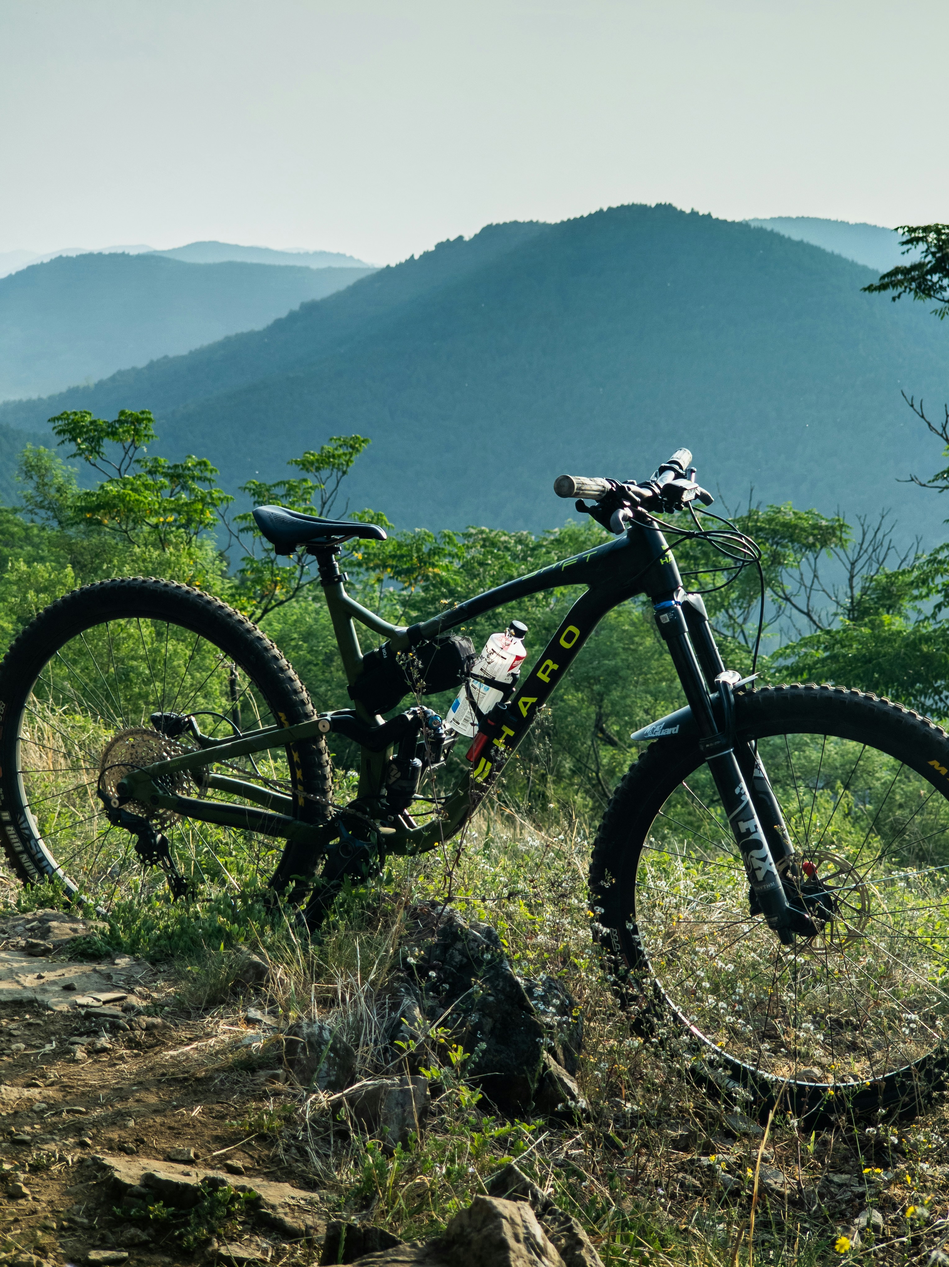 Black mountain bike on a dirt trail with hazy mountains.