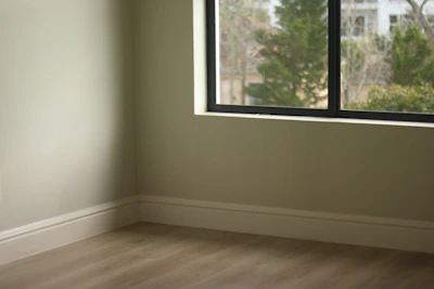 Empty room with light green walls, wooden floor, and window.