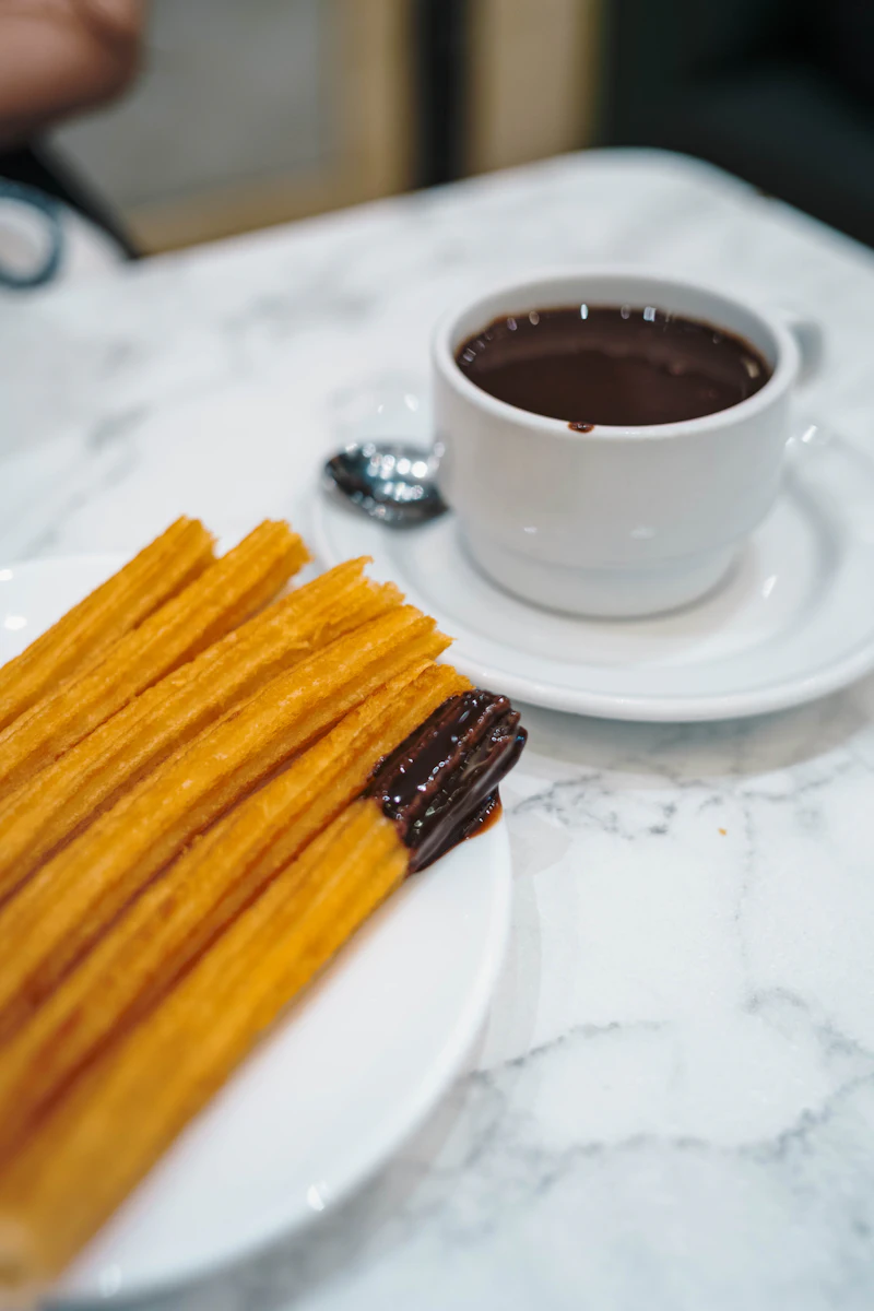 Churros recién fritos junto a una taza de chocolate caliente