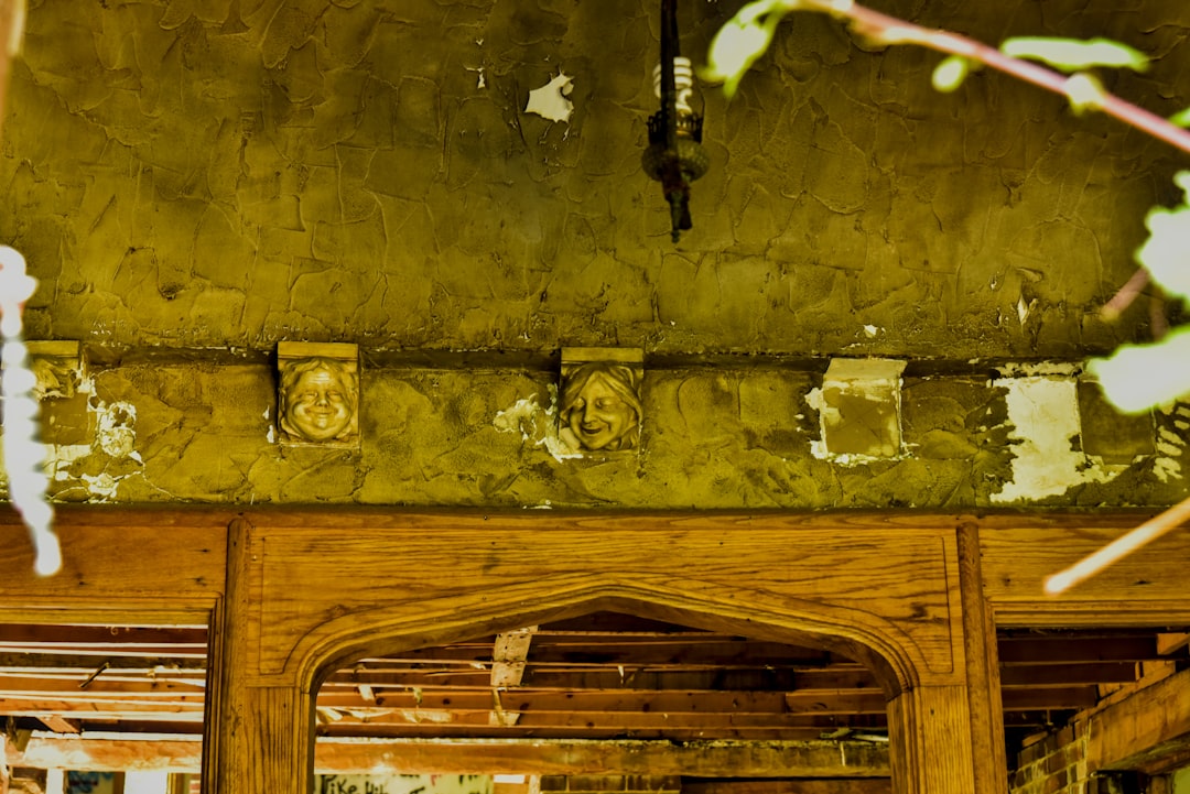 Old, peeling green wall above an ornate wooden structure.