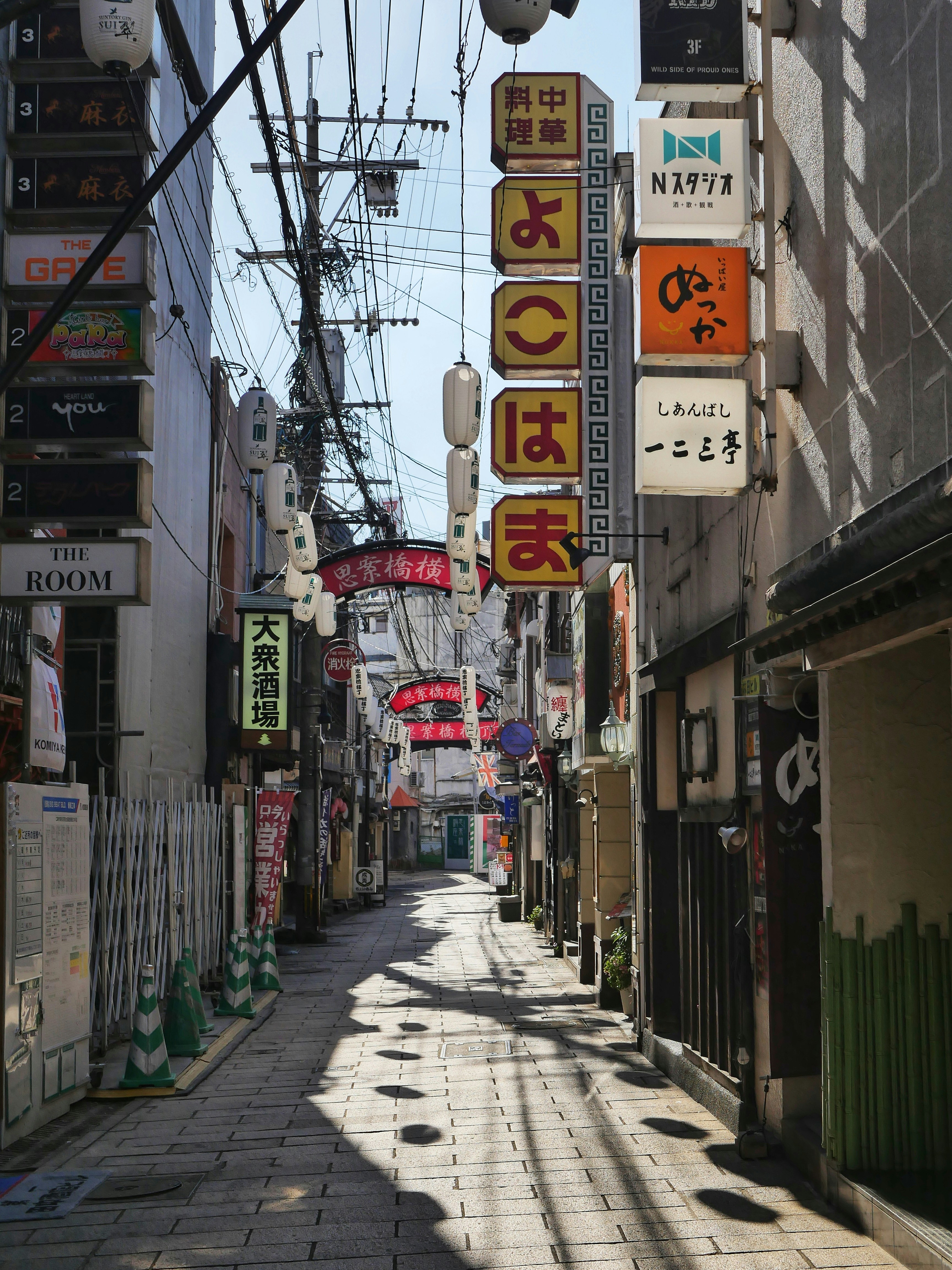Una calle japonesa estrecha llena de señales y cables aéreos.