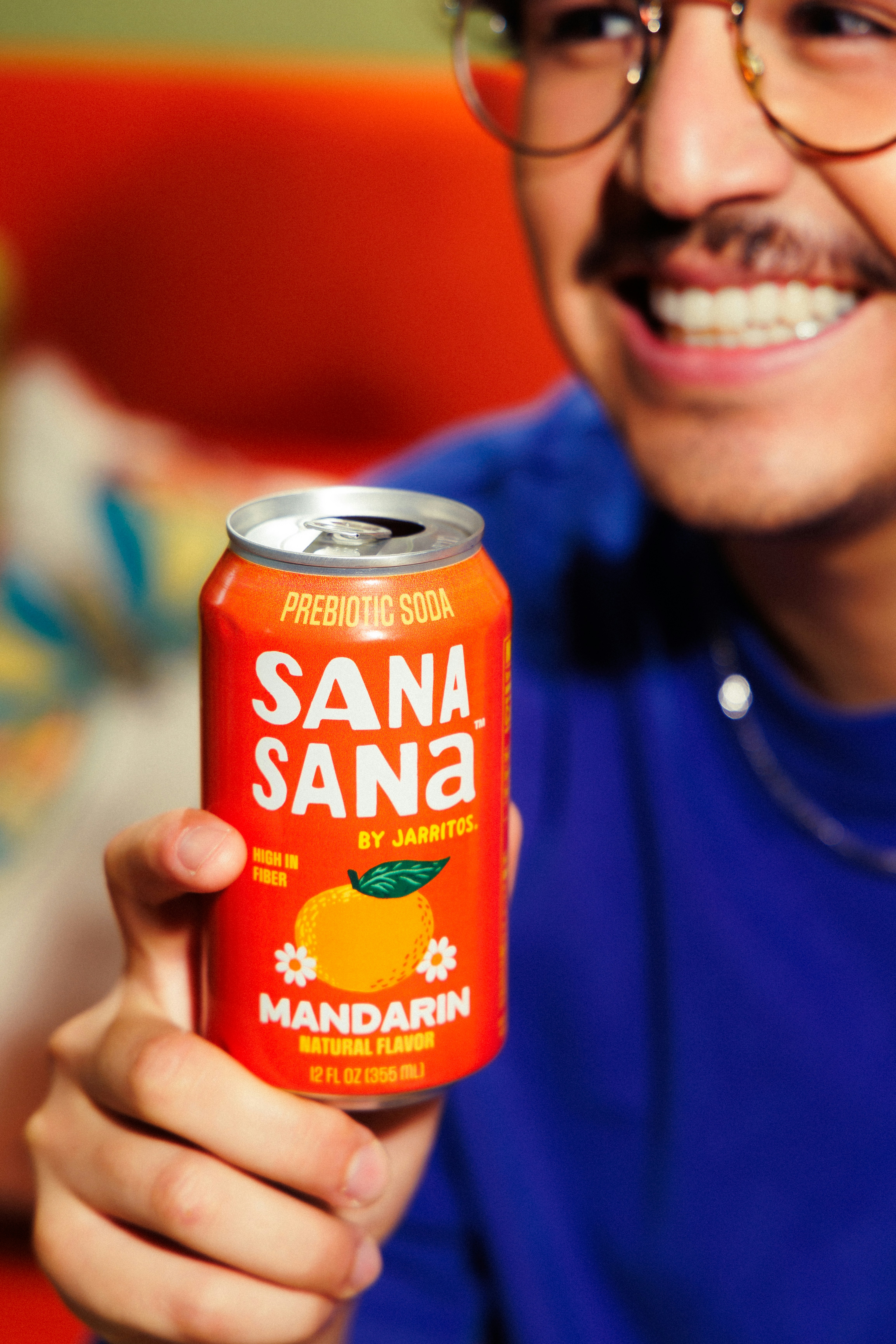 Hombre sonriente sosteniendo una soda prebiótica mandarín "sana sana".