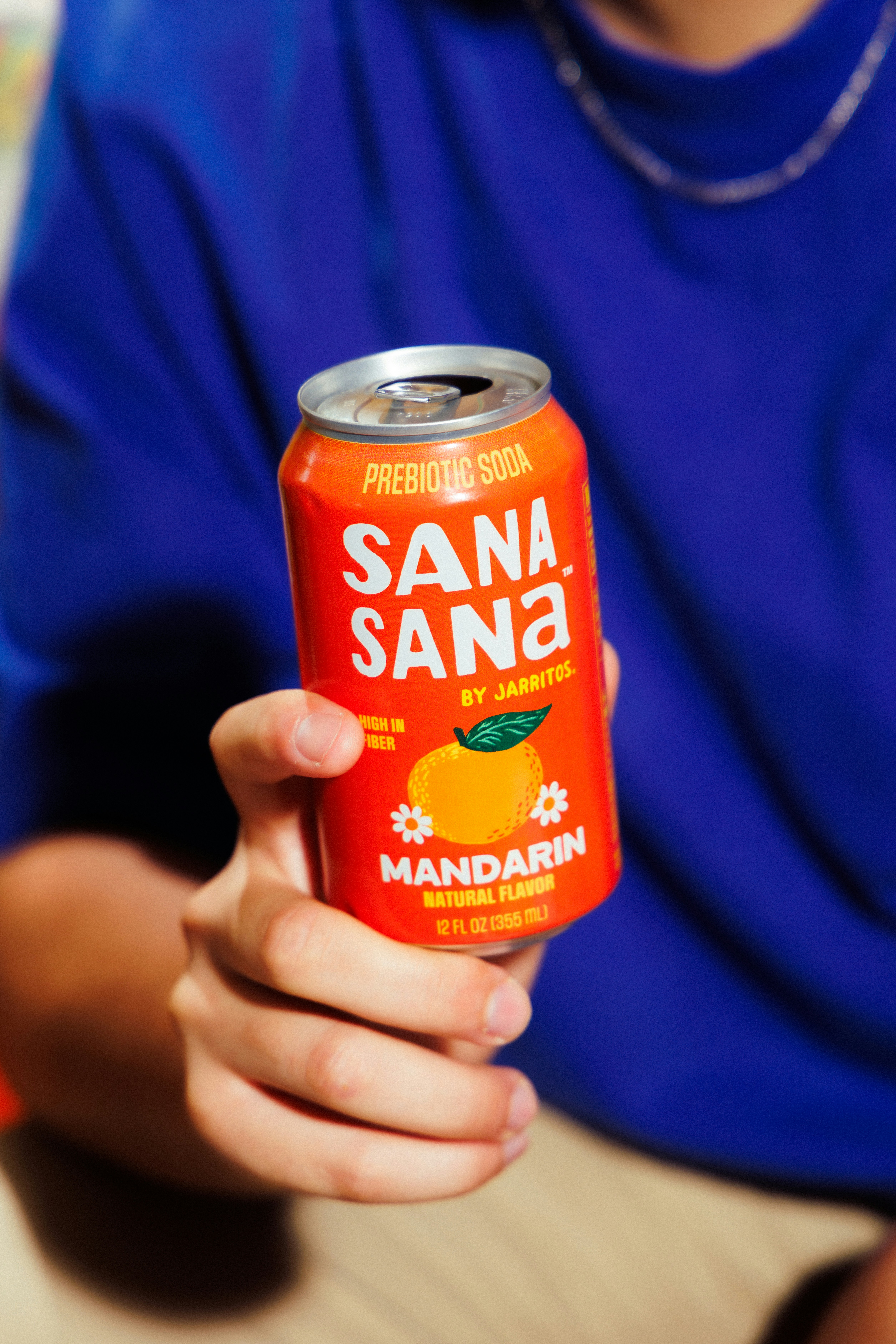 Persona sosteniendo una lata de refresco prebiótico mandarín sana sana.