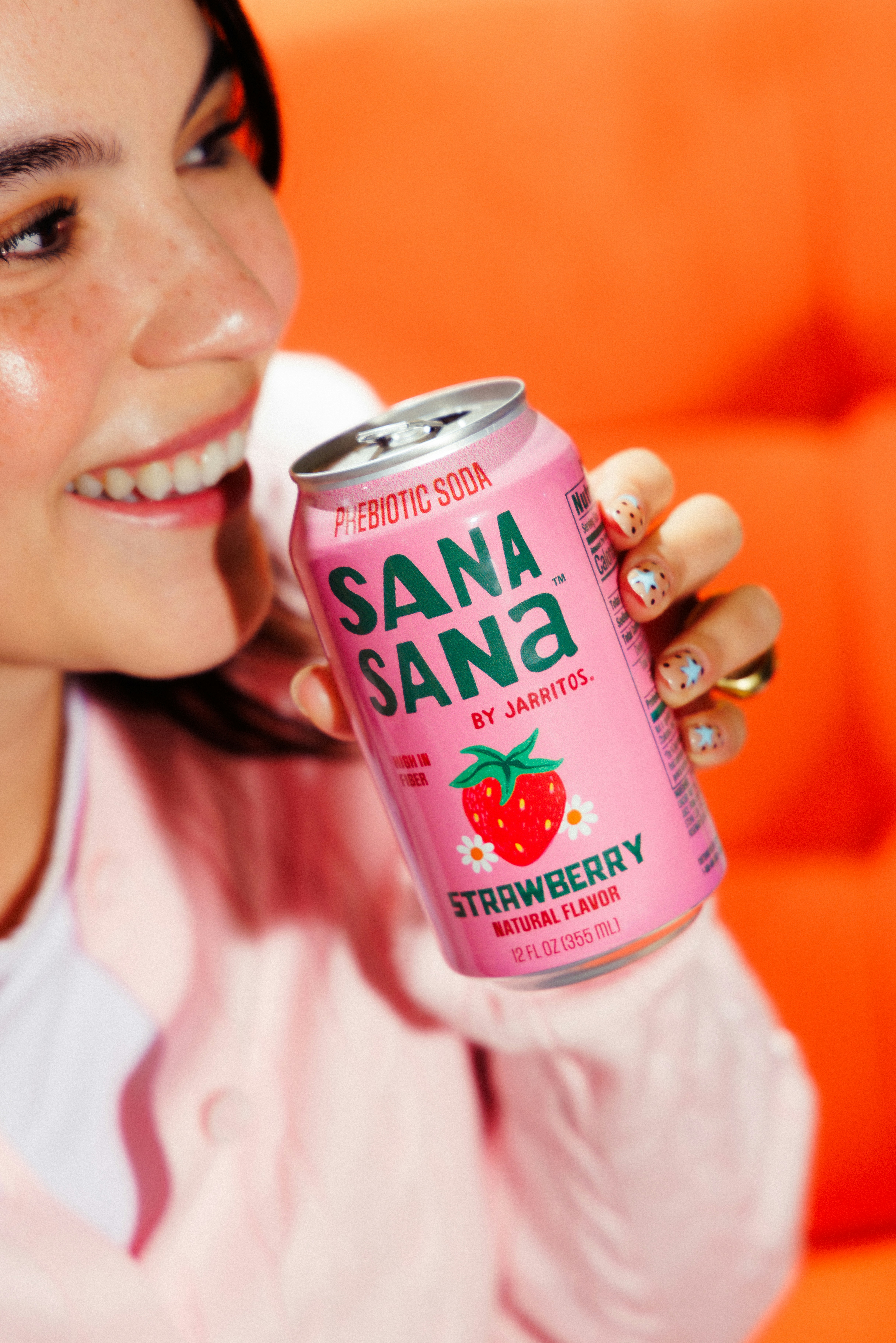 Mujer sonriente sosteniendo una lata de refresco rosa de fresa.