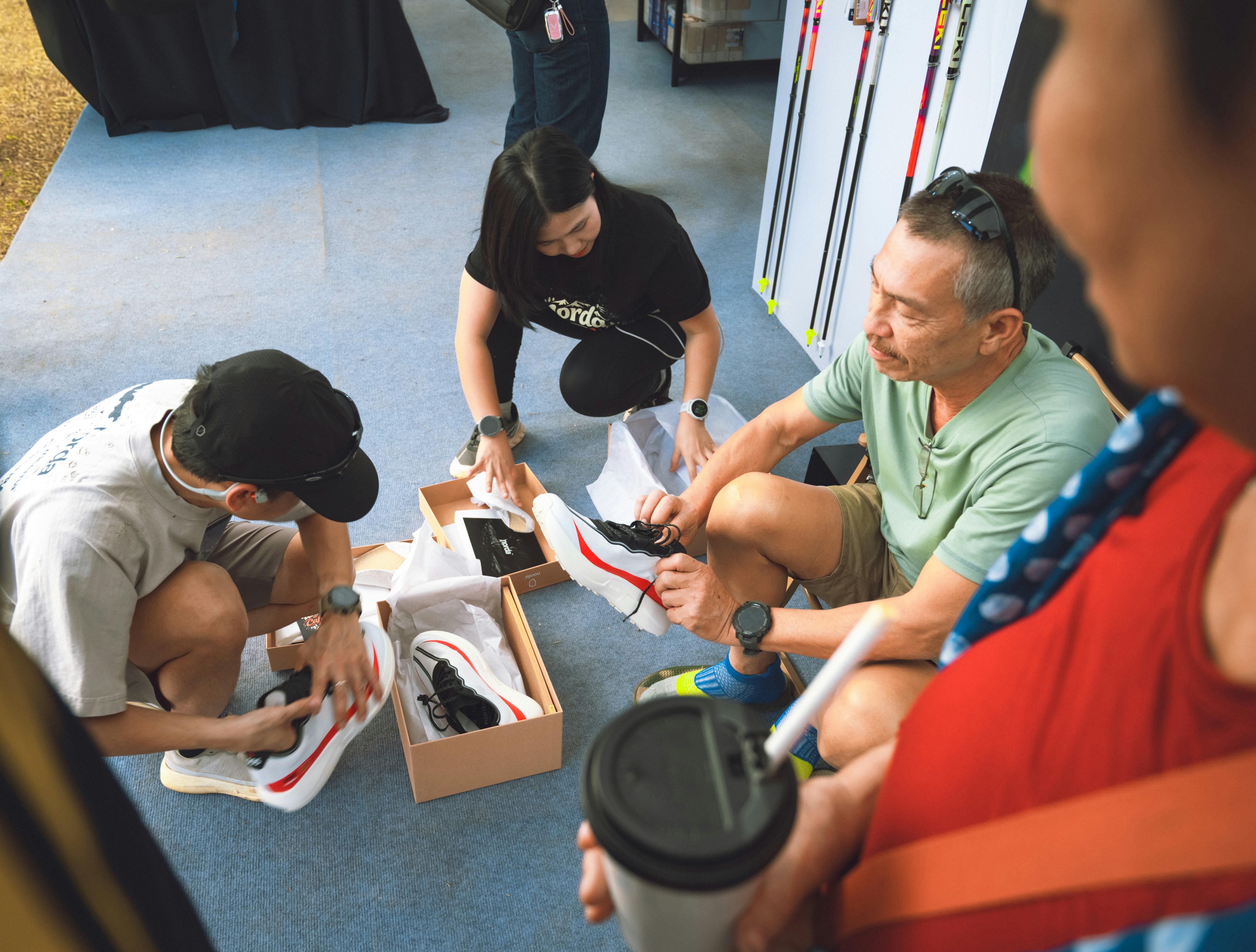 People examining new shoes in boxes on the ground.