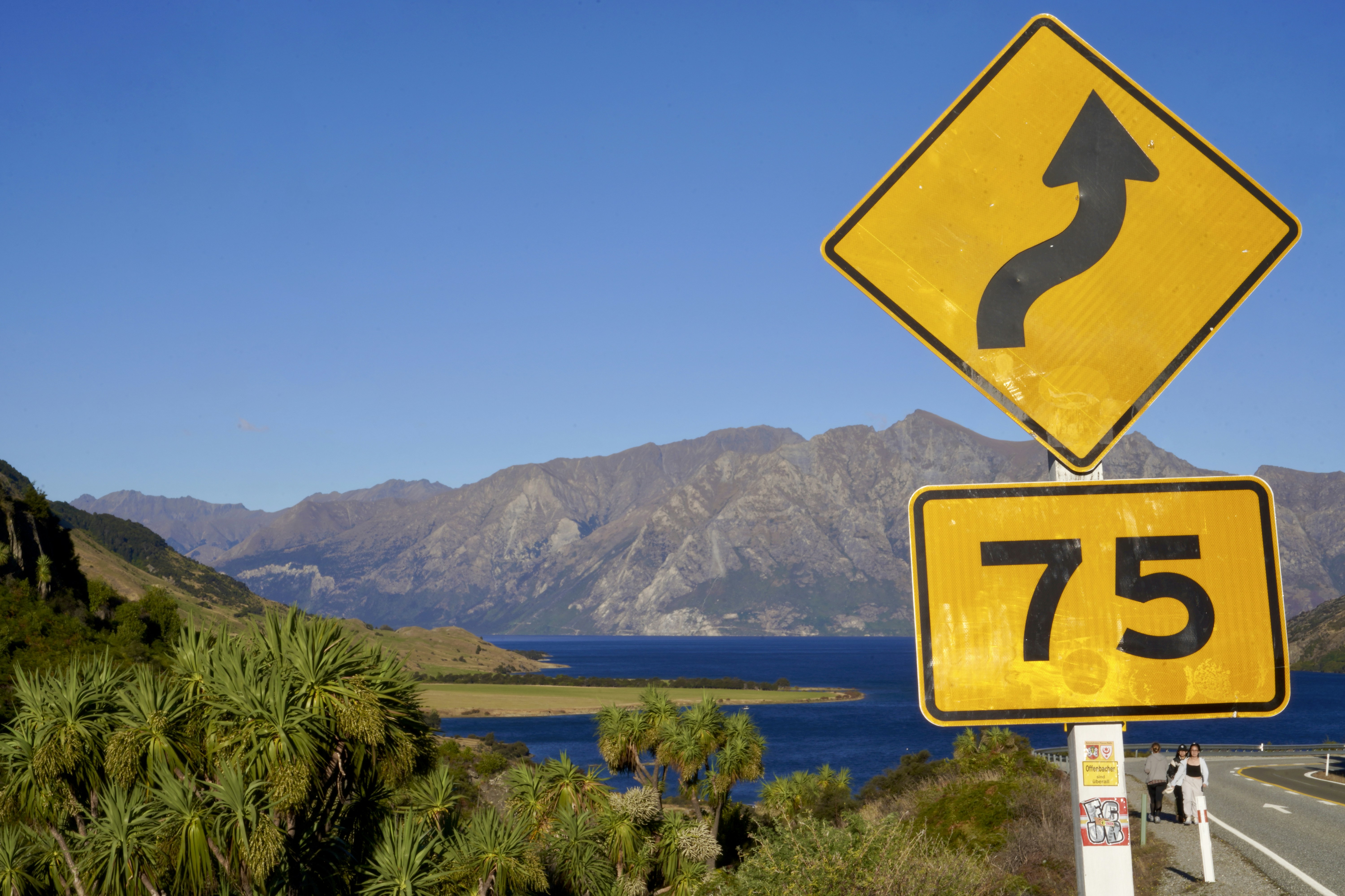 Winding road sign and 75 overlooking a mountain lake.