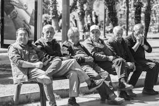 Six elderly men sitting together on a park bench.