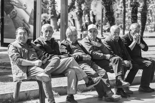 Six elderly men sitting together on a park bench.